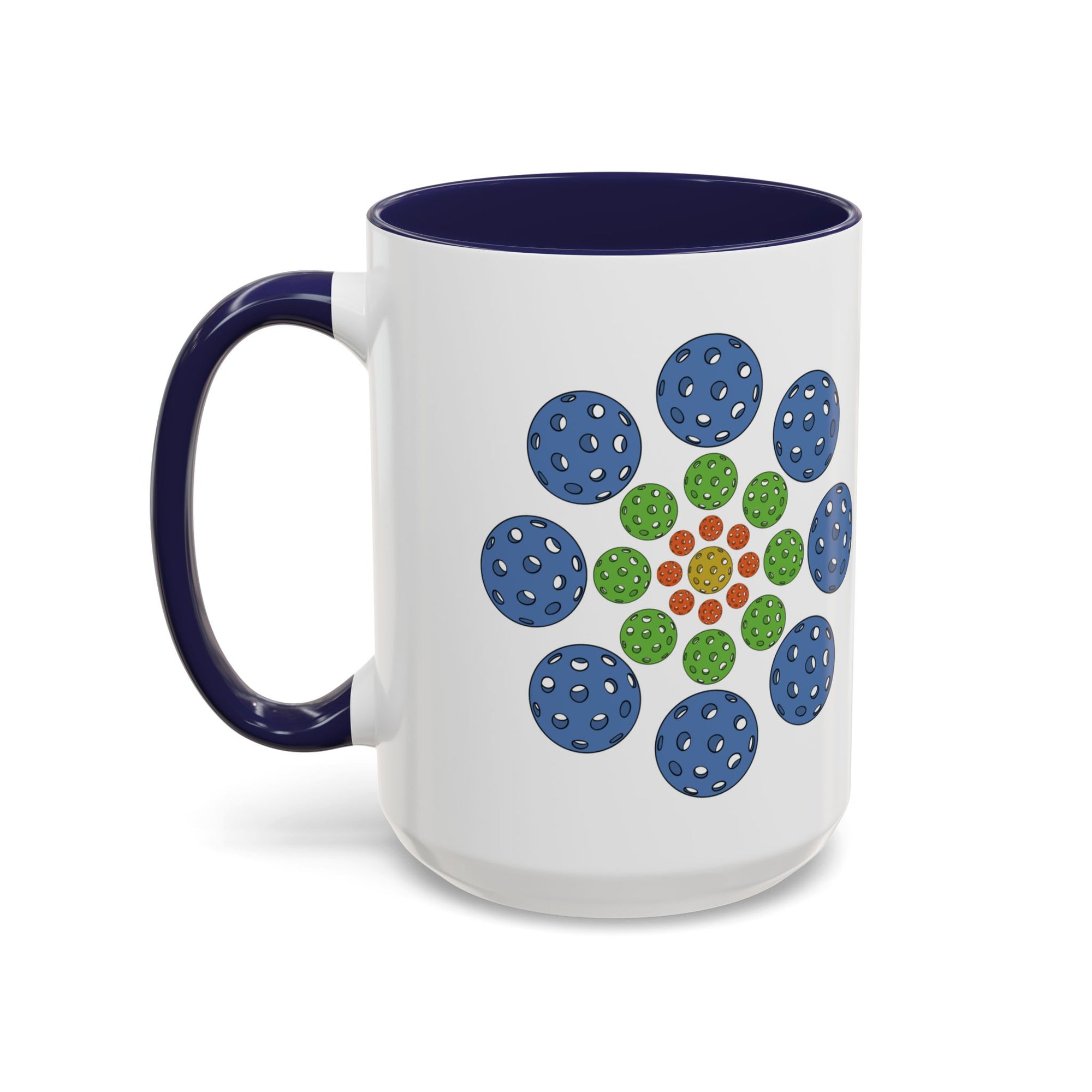 A ceramic coffee mug with dark blue accents on the handle and interior, with a colorful geometric design of pickleballs against a white background