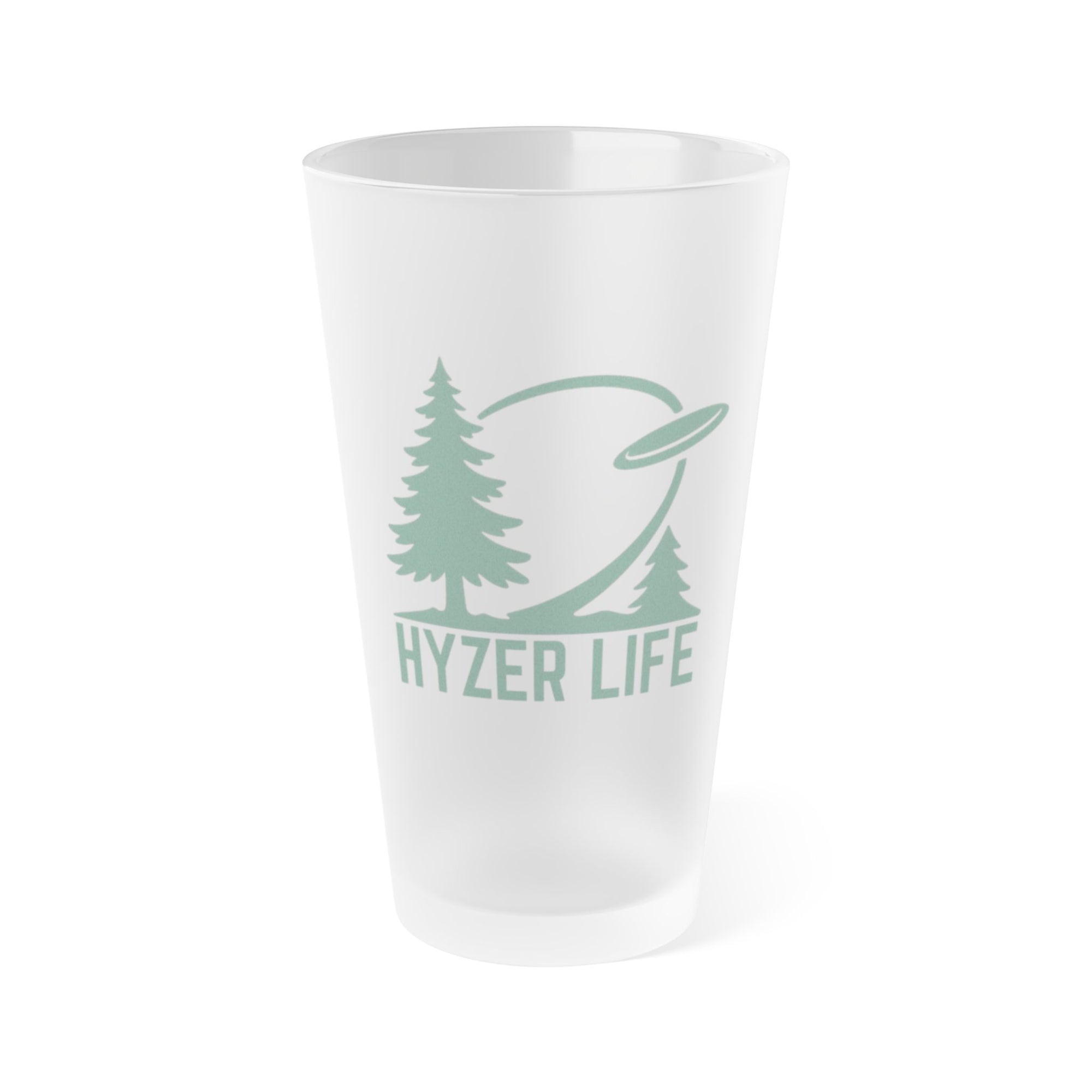 Frosted pint glass with a design that says Hyzer Life with a flying disc golf disc, basket, and chains along with trees in the background.