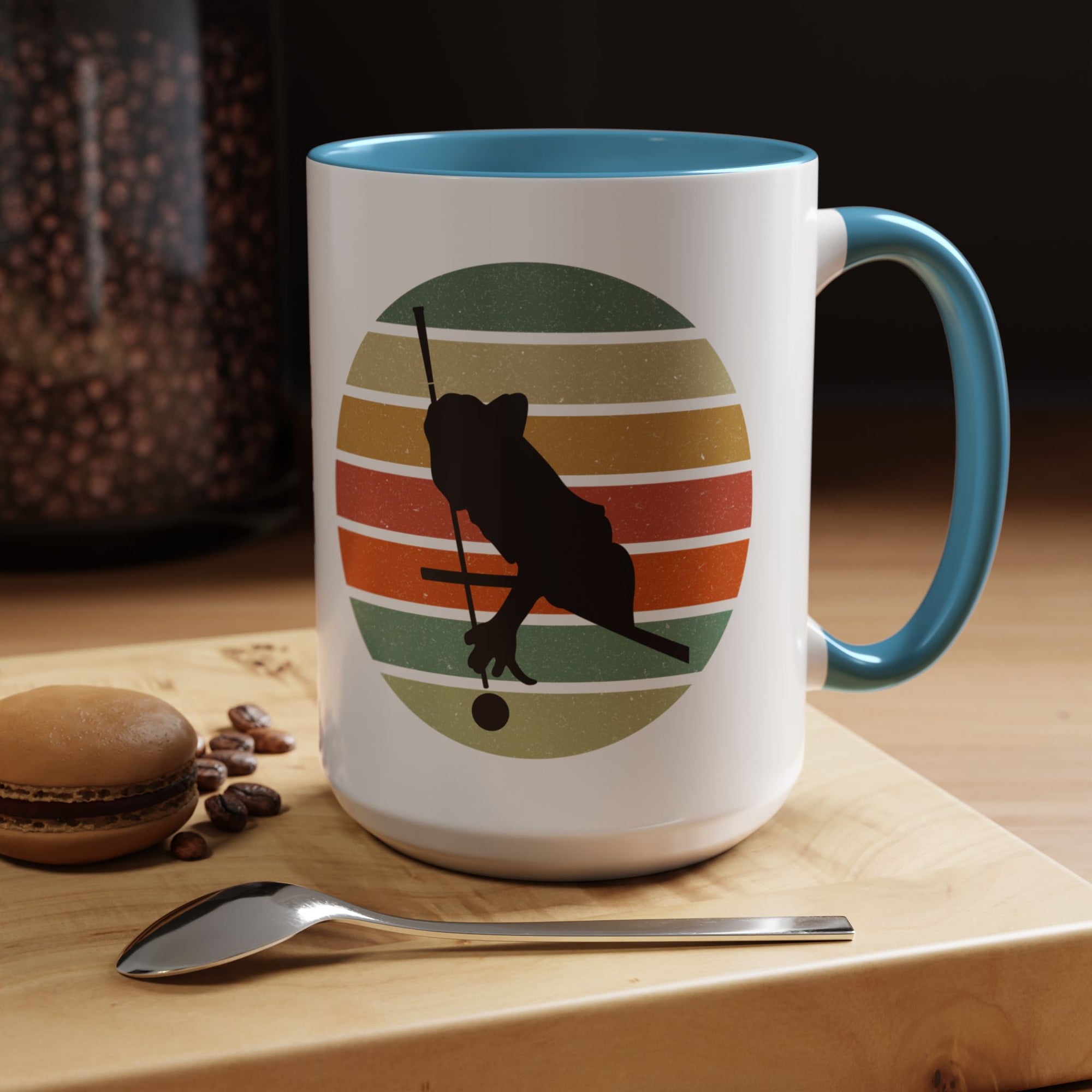 Mug with red accents and a graphic of a billiards player silhouette over a colorful retro design on cutting board with coffee beans, a spoon, and a cookie.