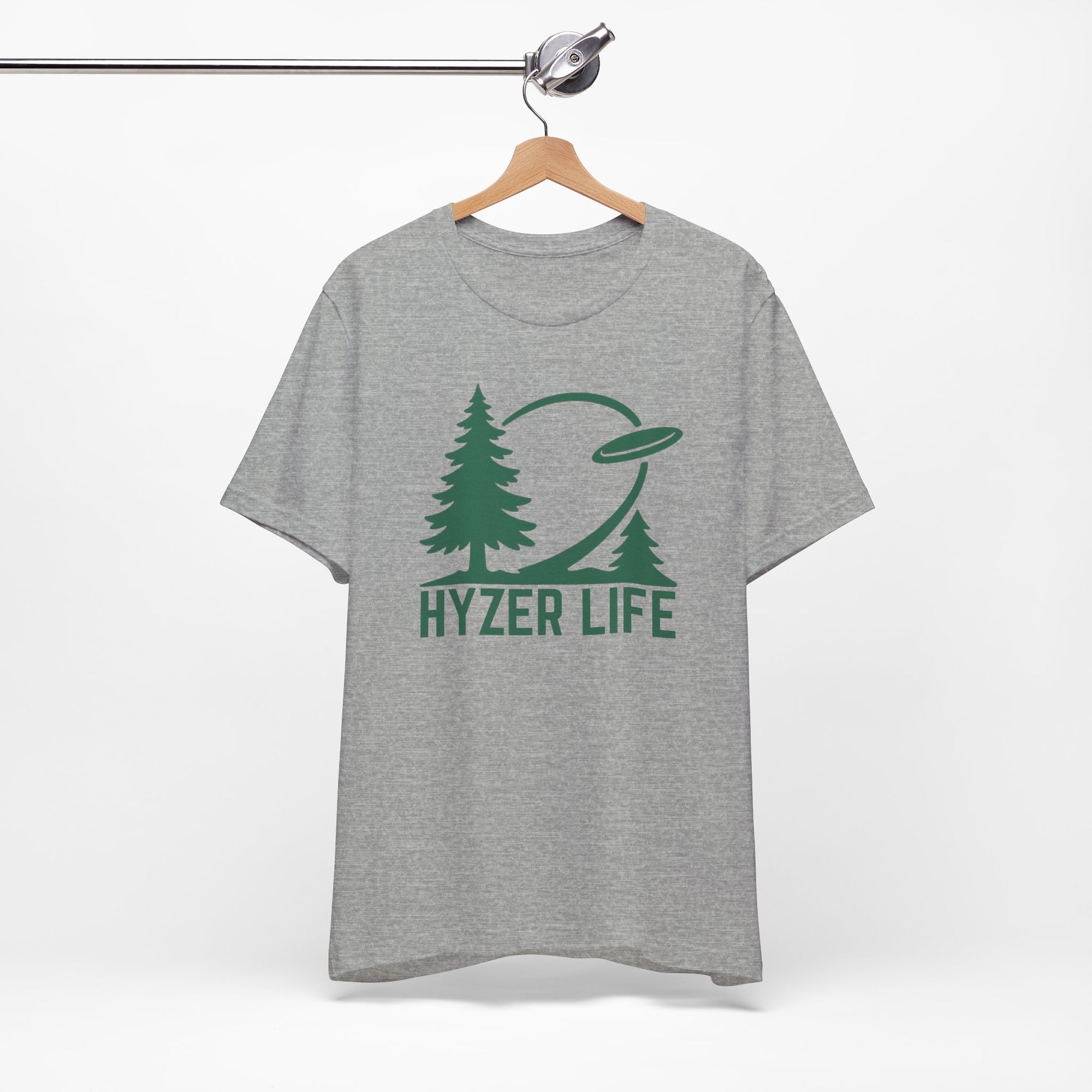 Gray t-shirt with green graphic of trees and a disc golf flying with the words 'HYZER LIFE' below the image, on a hanger against a white backgroud