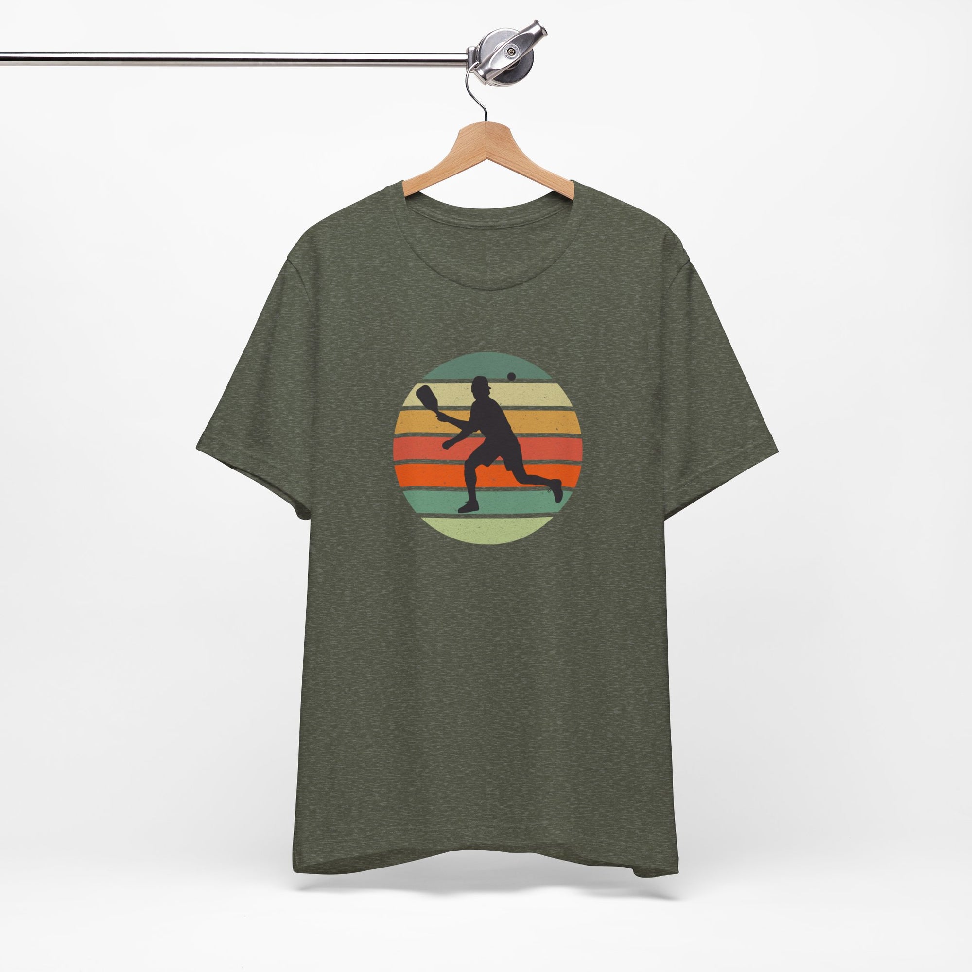 Green t-shirt with a colorful graphic of a person playing pickleball on a hanger against a white background