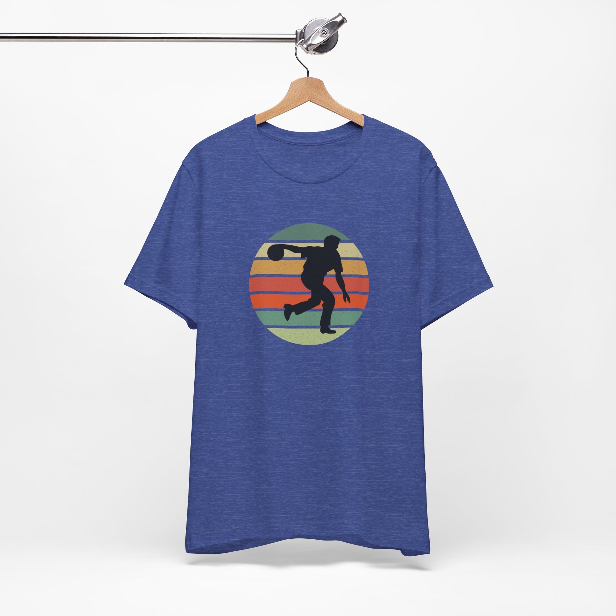 Blue t-shirt with a graphic of a silhouette of a bowler over a colorful retro image, hanging on a wooden hanger against a white background.