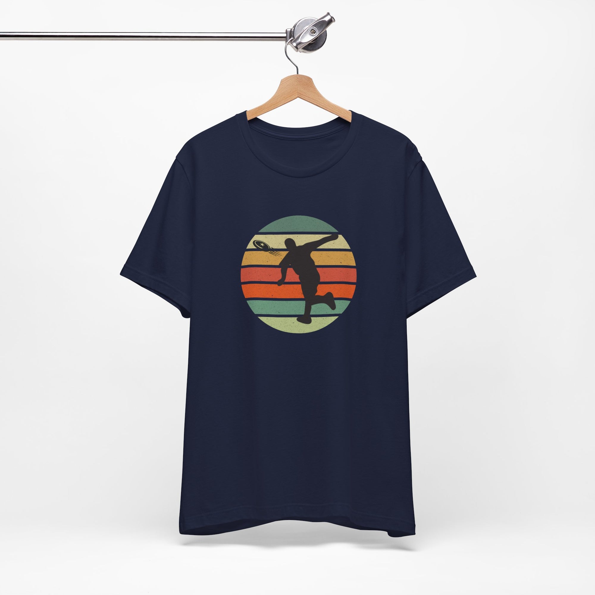 Navy blue t-shirt with a graphic of a silhouette disc golf player throwing a disc above a colorful retro graphic, hanging on a wooden hanger.