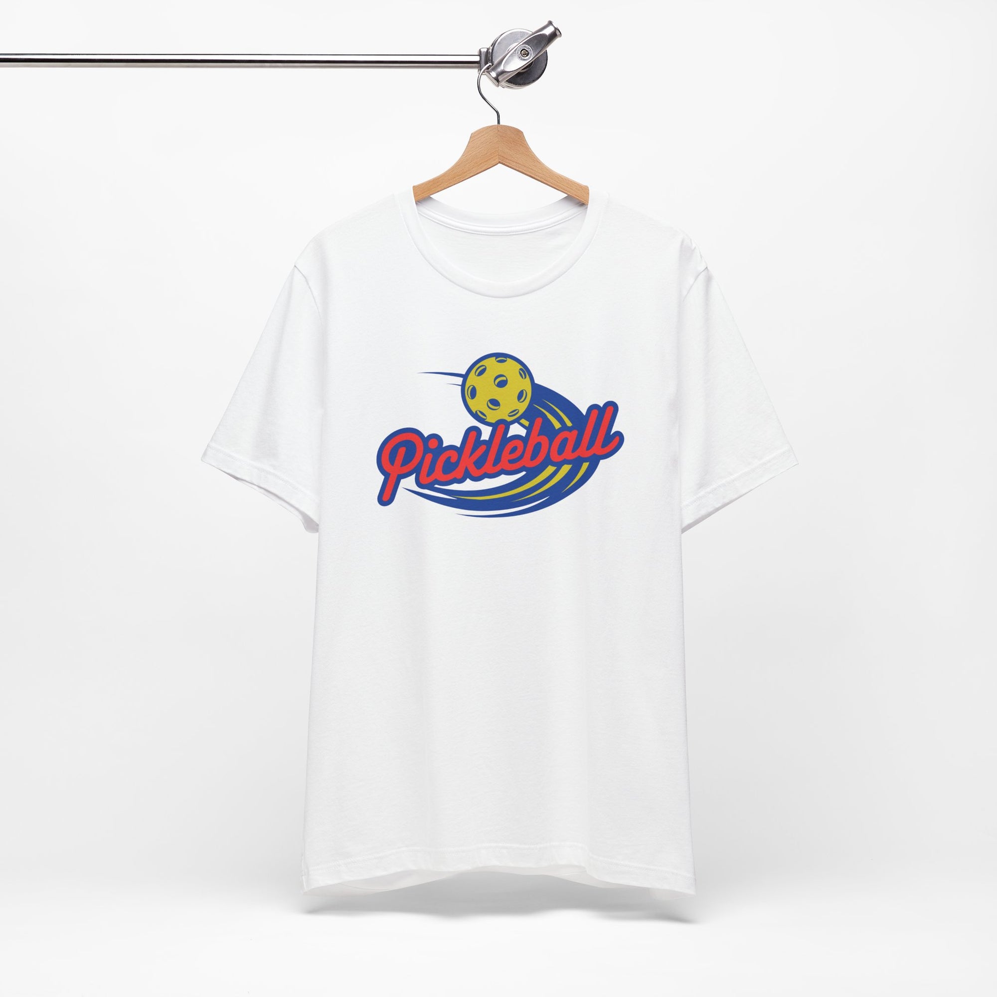 White t-shirt with a classic pickleball logo featuring the word pickleball and a yellow pickleball with motion lines, on a hanger against a white background