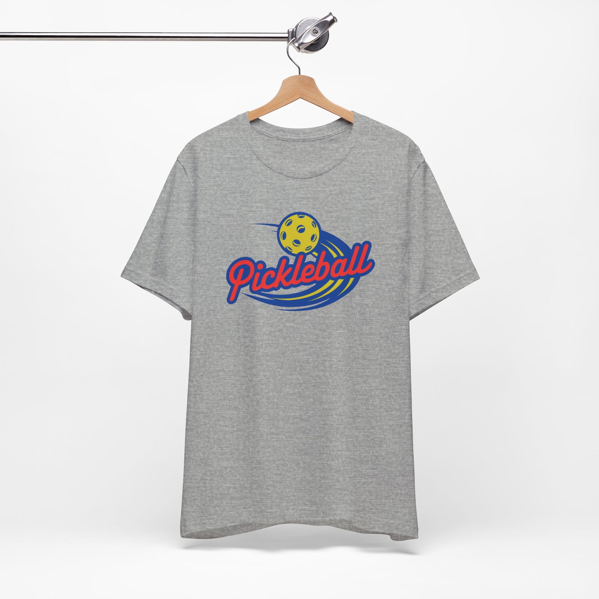 Light gray t-shirt with a classic pickleball logo featuring the word pickleball and a yellow pickleball with motion lines, on a hanger against a white background