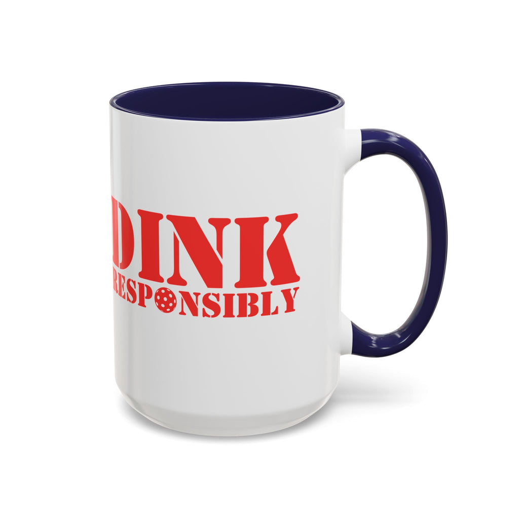 A ceramic coffee mug with dark blue accents on the handle and interior, with red text 'DINK RESPONSIBLY' with a pickleball replacing the "O" in "Responsibly" against a white background