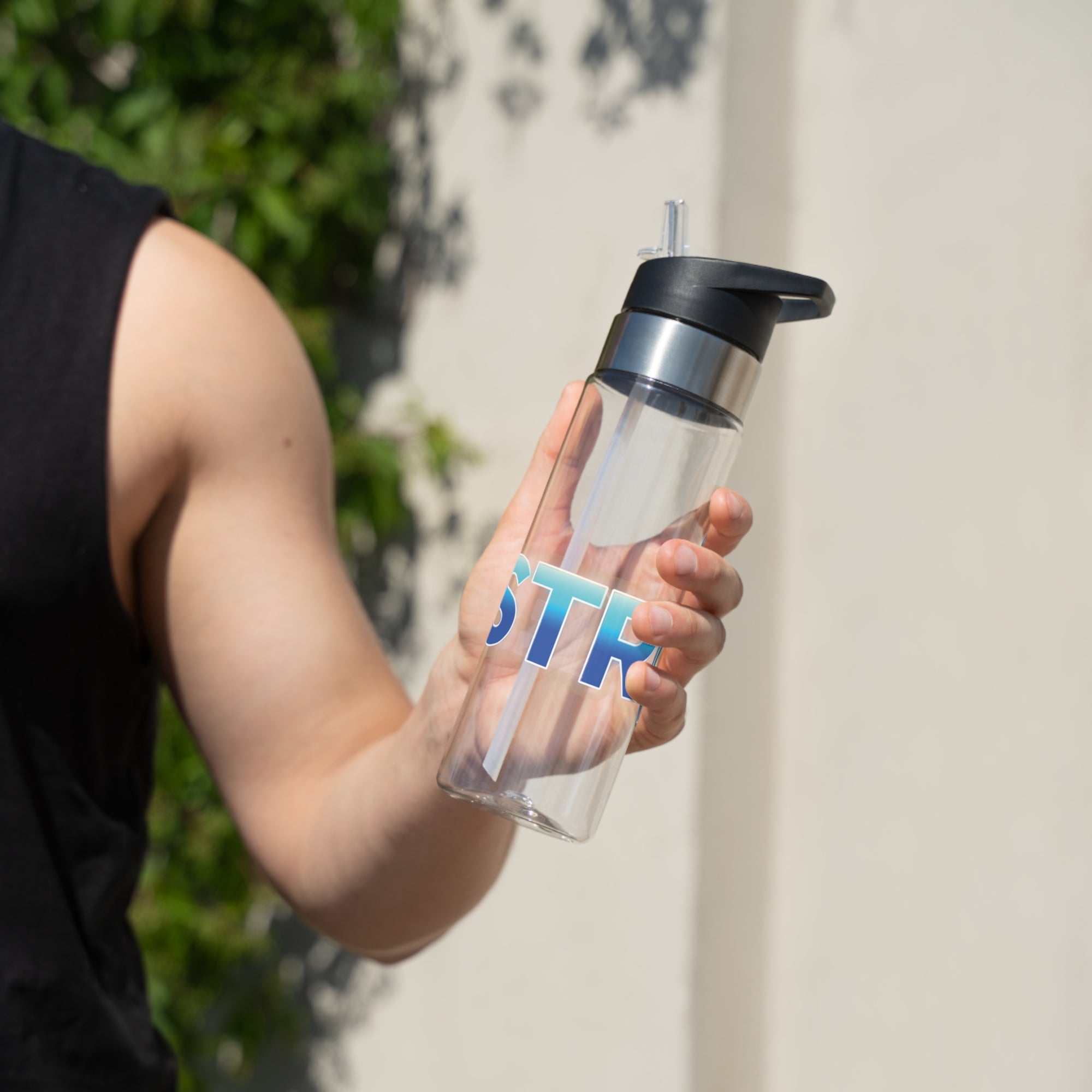A person holding a clear water bottle with black lid, with 'STRIKE!' with the "I" replaced by a bowling pin