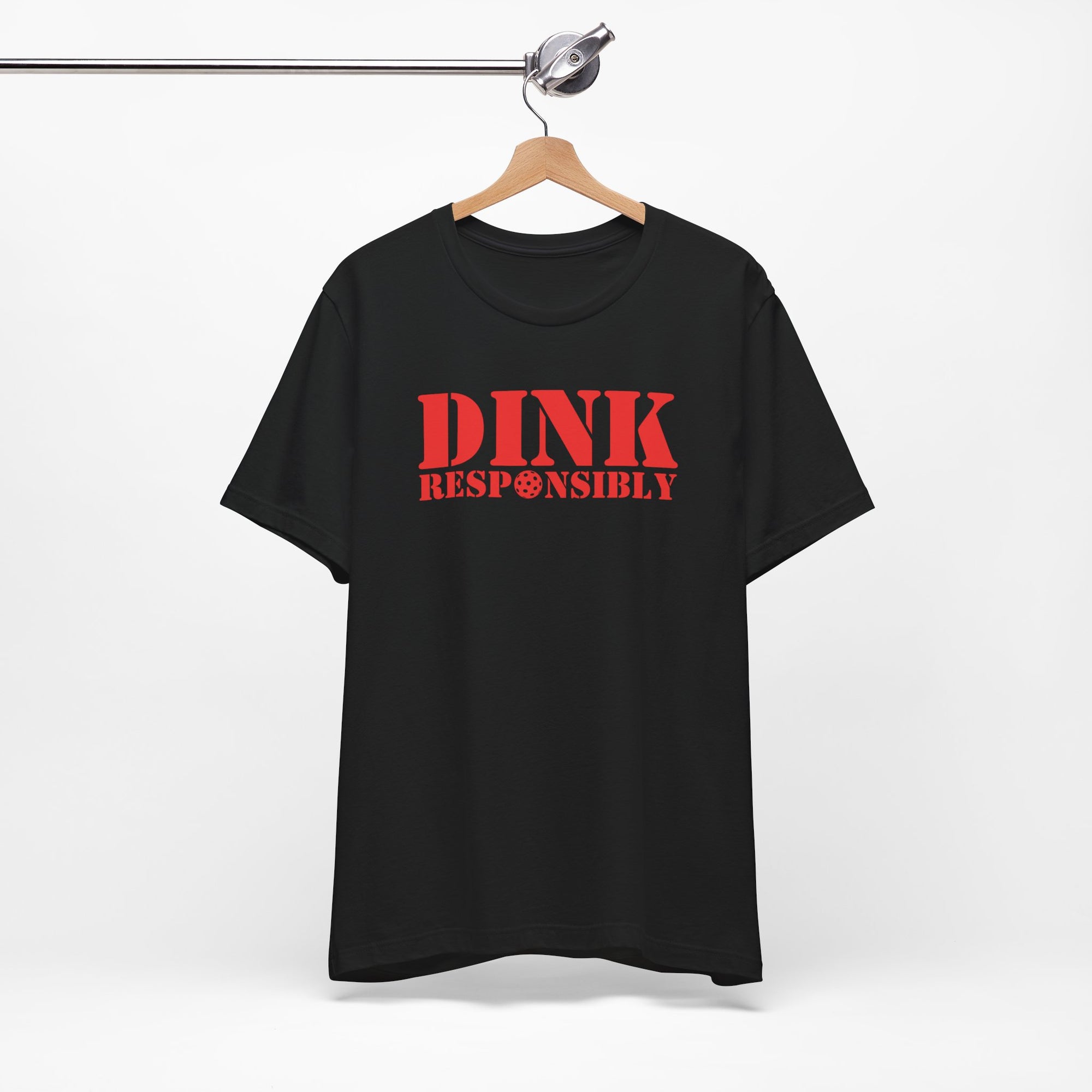 Black t-shirt with red text 'DINK RESPONSIBLY' with a pickleball replacing the "O" in "Responsibly" on a hanger against a white background