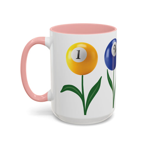 A white ceramic coffee mug with pink accents on the handle and interior, with four colorful flowers made out of billiards balls with green stems, on a white background