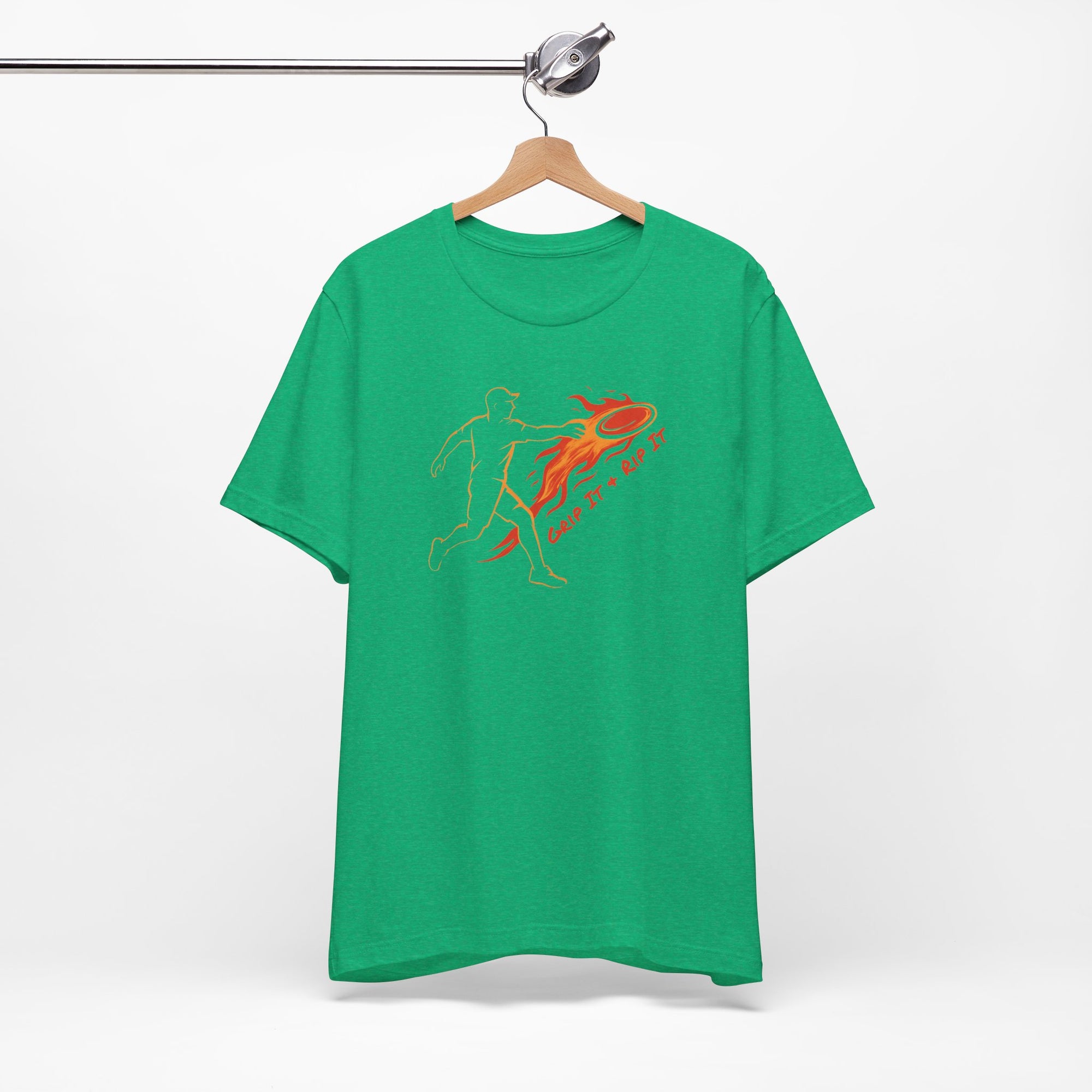 Green t-shirt with a graphic design of a person throwing a disc golf disc with flames coming off the disc and text 'Grip It or Rip It' on a hanger against a white background.