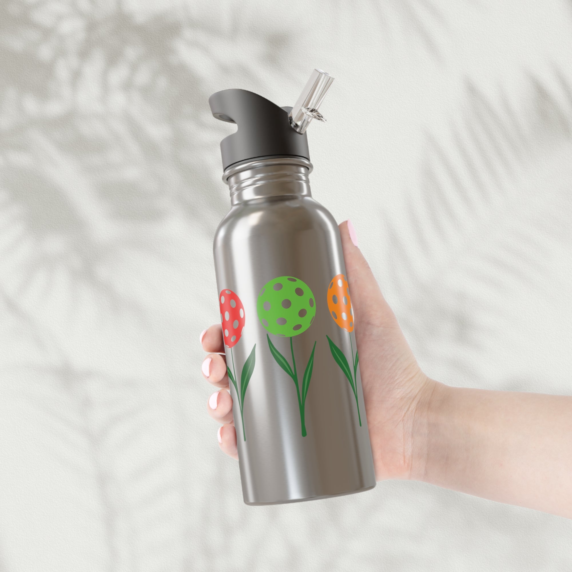 A stainless steel water bottle with lid featuring colorful flowers made from pickleballs on green stems with leaves, against a white background