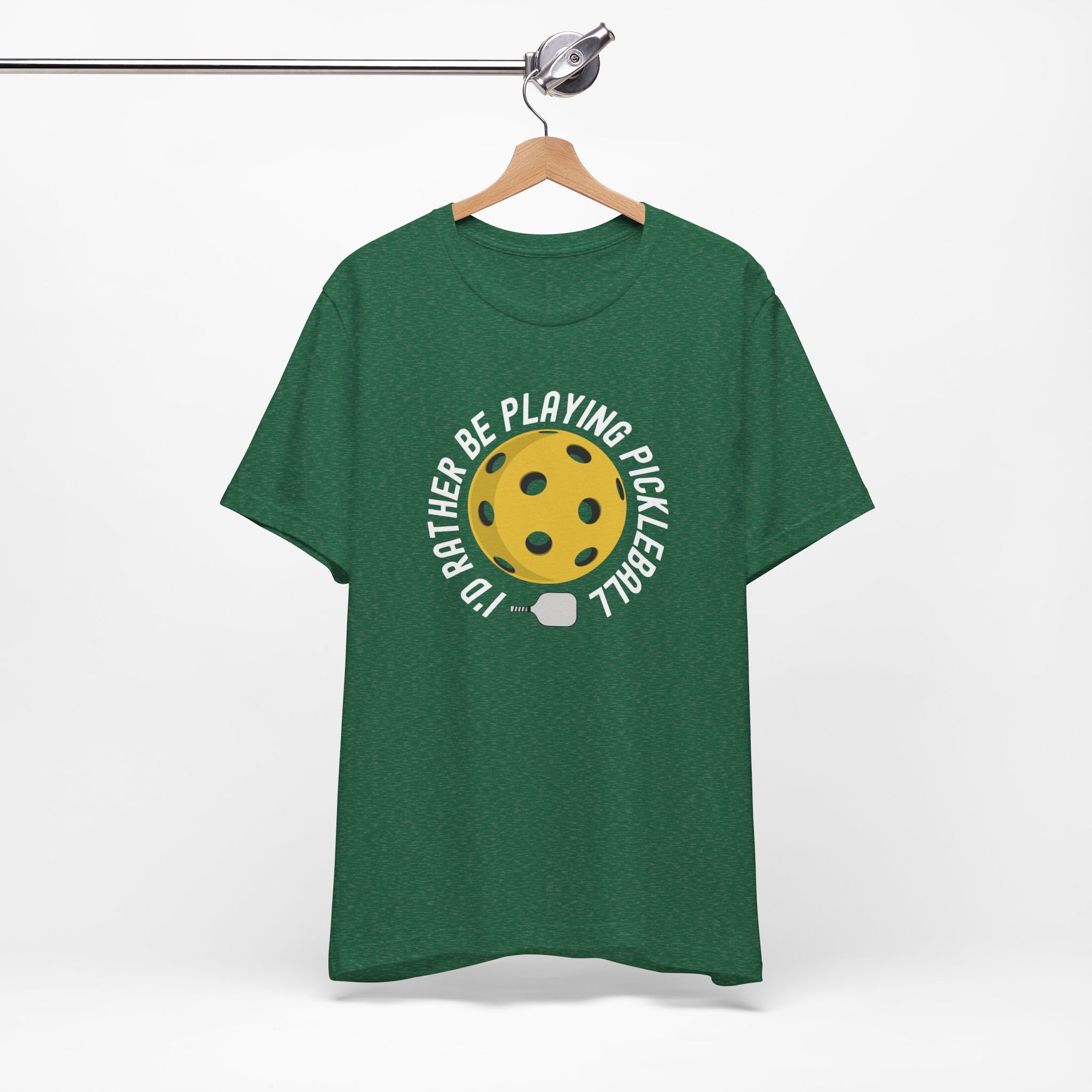 Green t-shirt with a yellow pickleball and white pickleball paddle and the text "I'd Rather Be Playing Pickleball" on a hanger against a white background