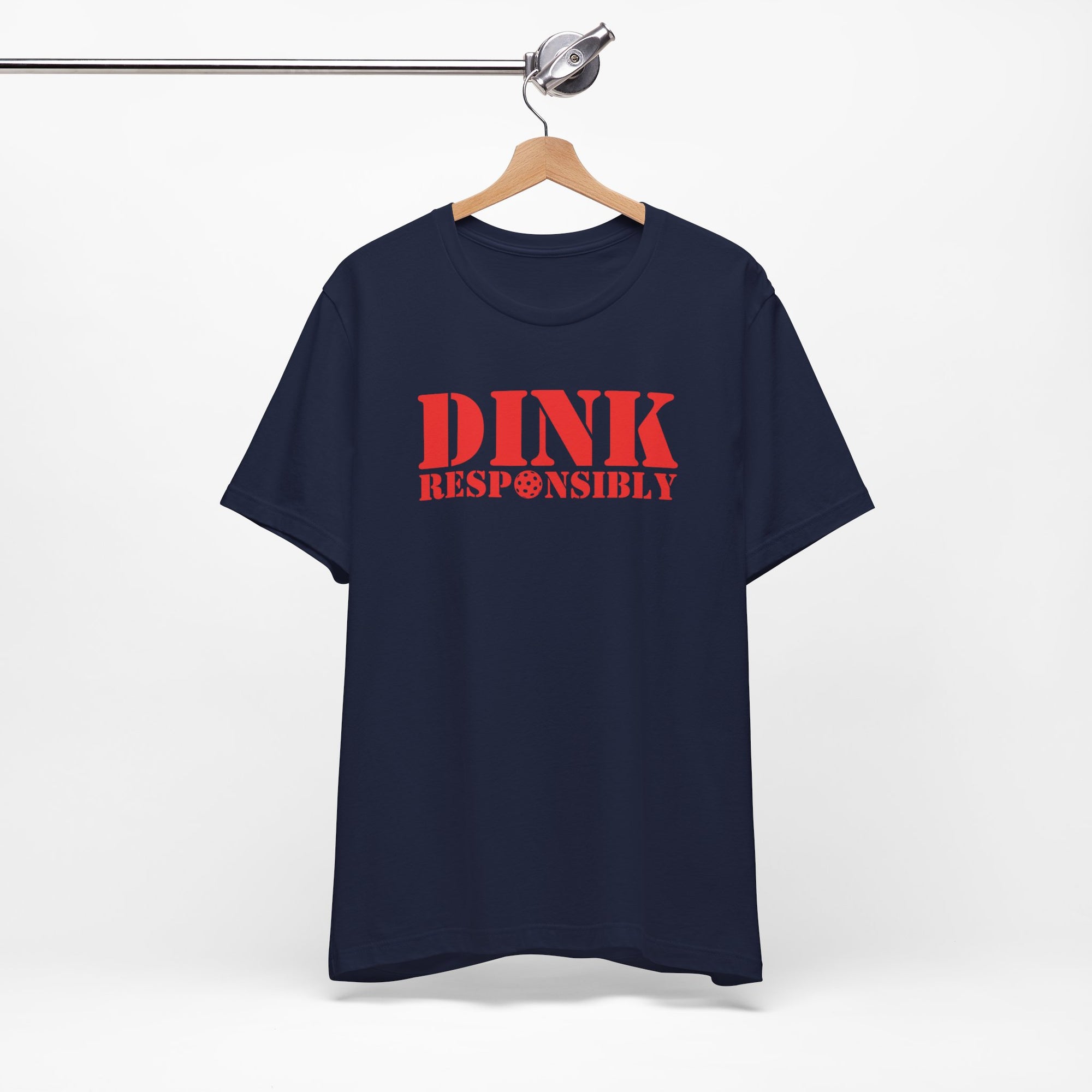 Navy blue t-shirt with red text 'DINK RESPONSIBLY' with a pickleball replacing the "O" in "Responsibly" on a hanger against a white background