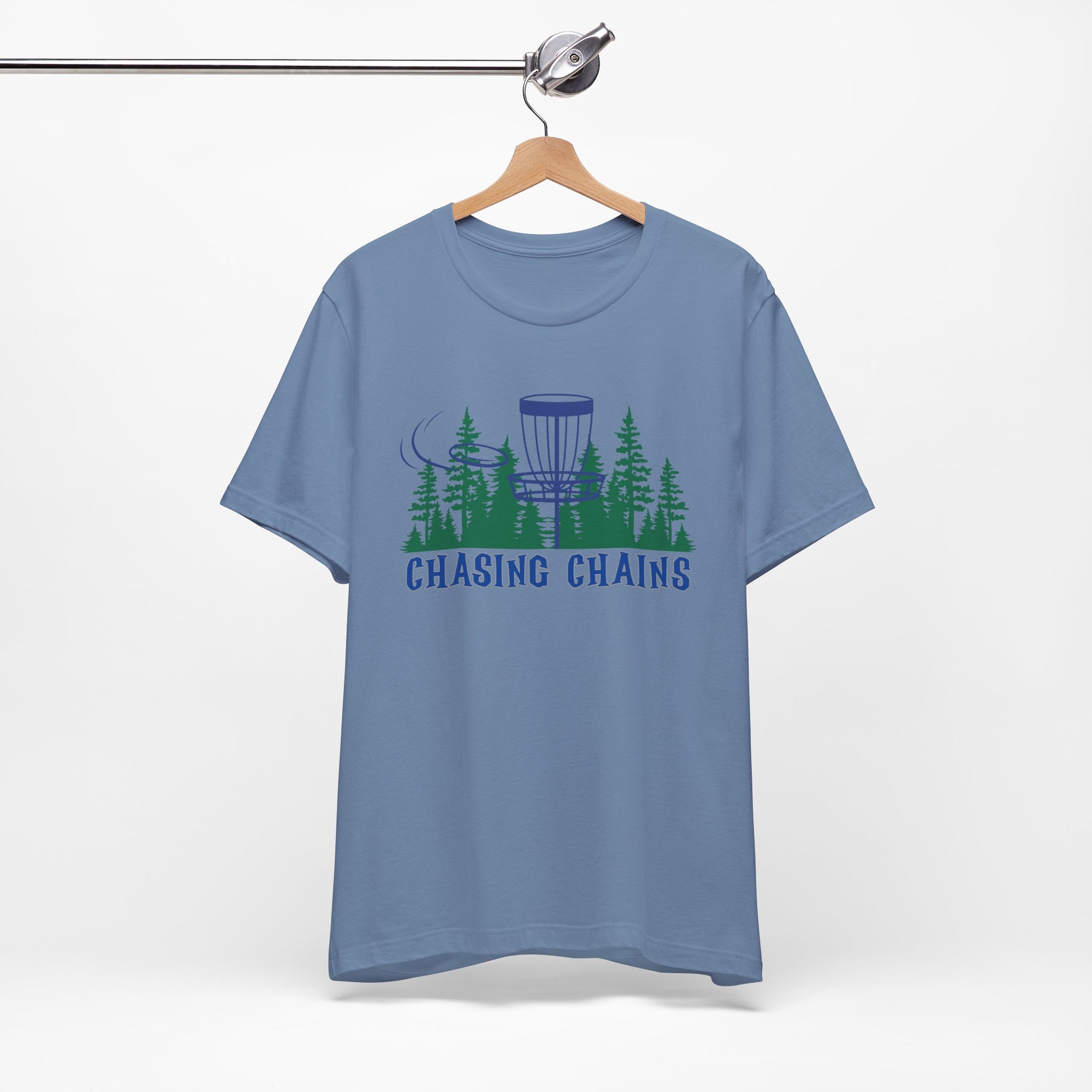 Steel blue t-shirt with 'Chasing Chains' graphic featuring a flying disc golf disc and basket and chains in front of a scenic evergreen tree landscape, on a hanger against a white background