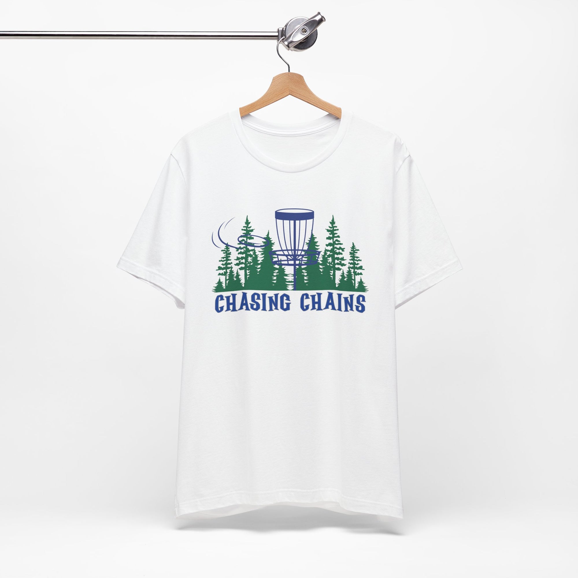 White t-shirt with 'Chasing Chains' graphic featuring a flying disc golf disc and basket and chains in front of a scenic evergreen tree landscape, on a hanger against a white background