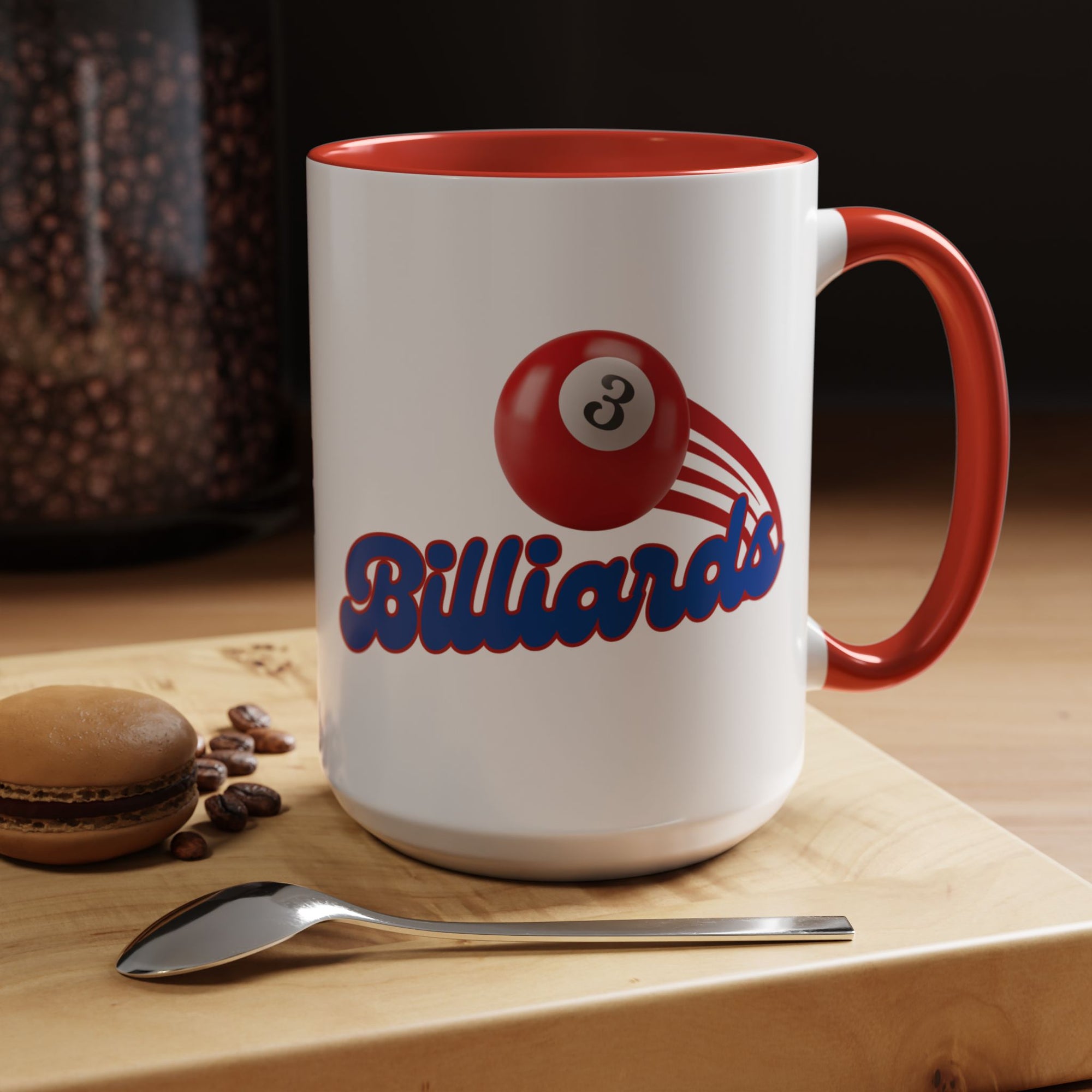 A white ceramic coffee mug with red accents on the handle and interior, with billiards ball and text that says "Billiards" in a coffee shop setting