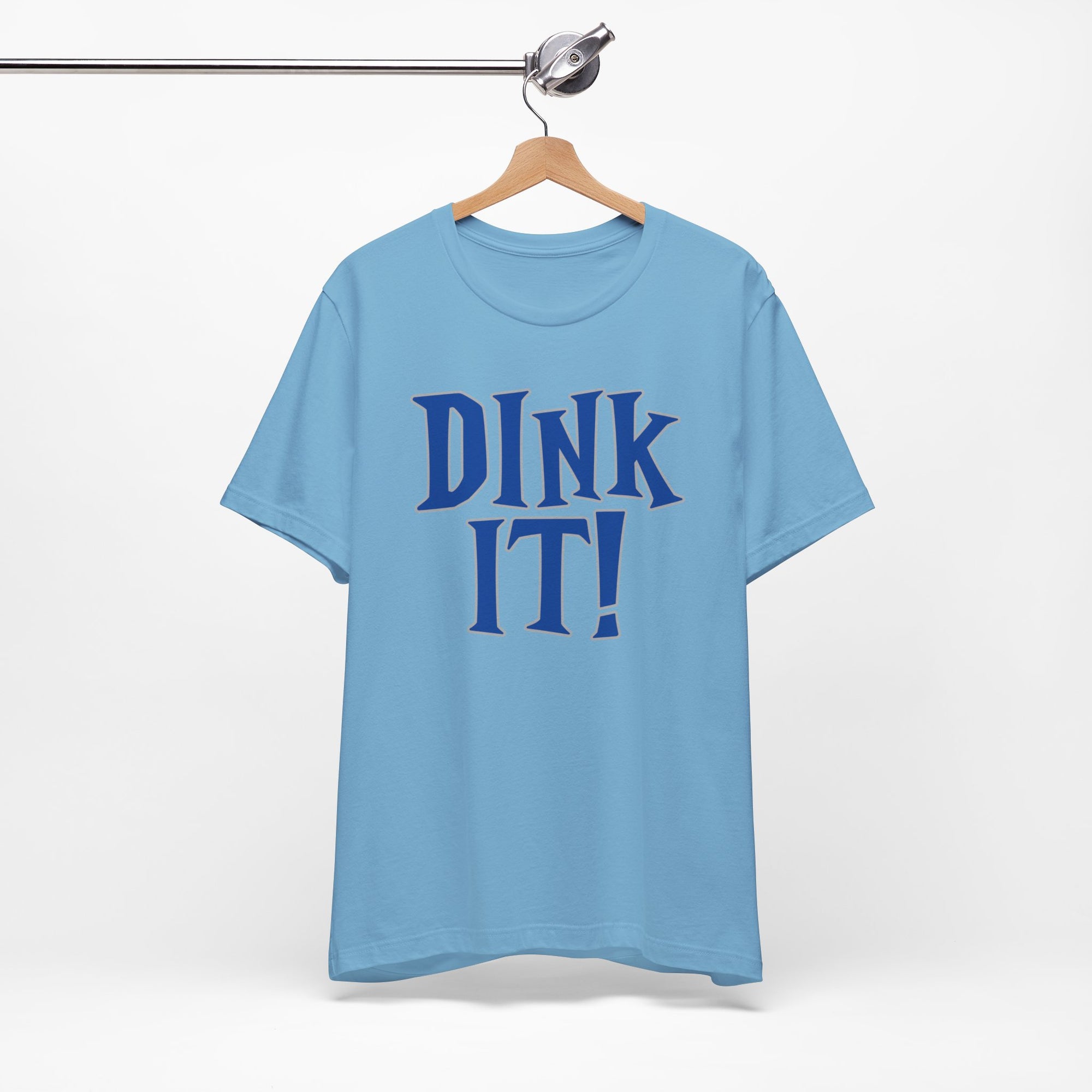 Light blue t-shirt with 'DINK IT!' text in blue and outlined in gray, on a hanger against a white background