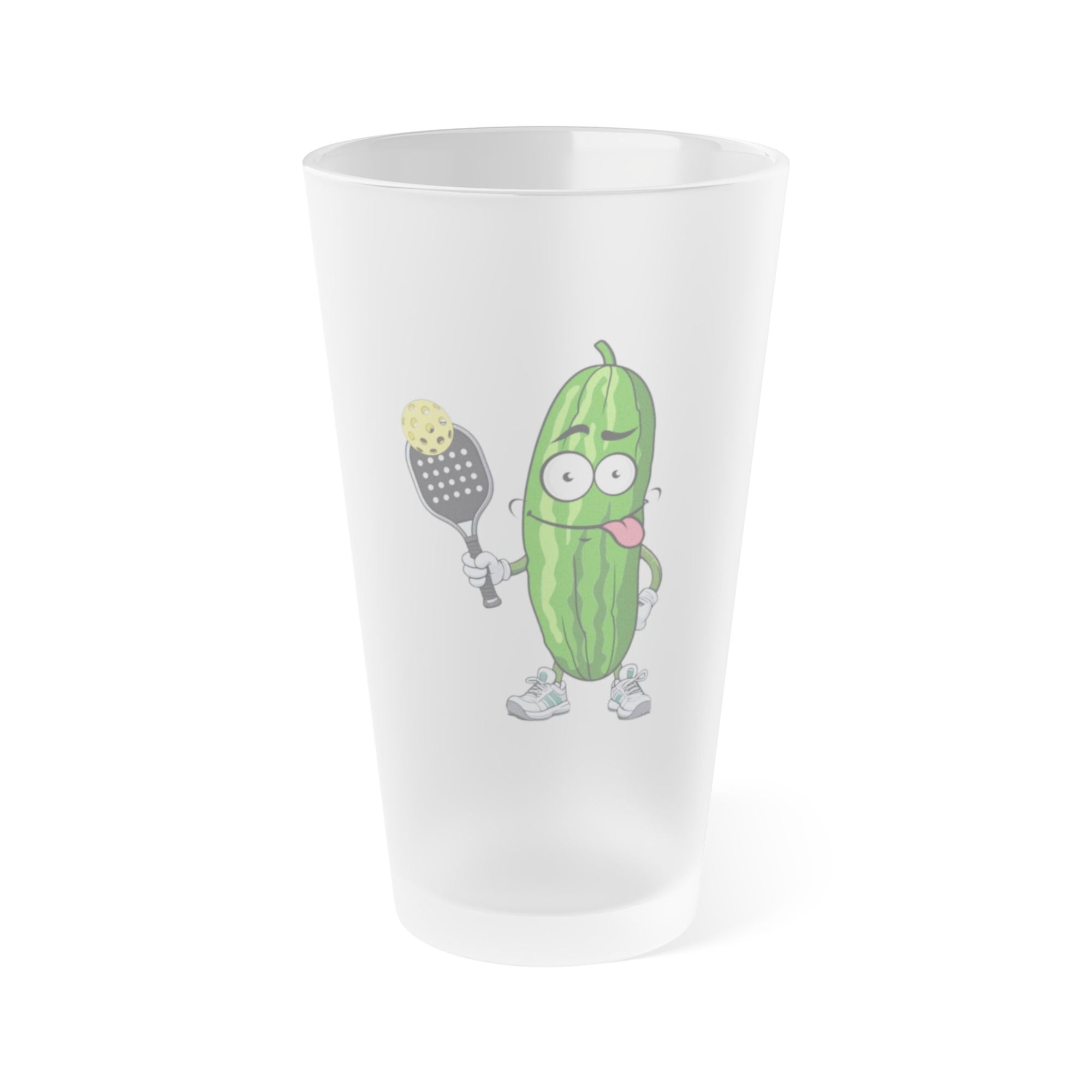 A frosted pint glass featuring an image of a cartoon pickle with googly eyes and his tongue sticking out, holding a pickleball paddle with a yellow pickleball, against a white background