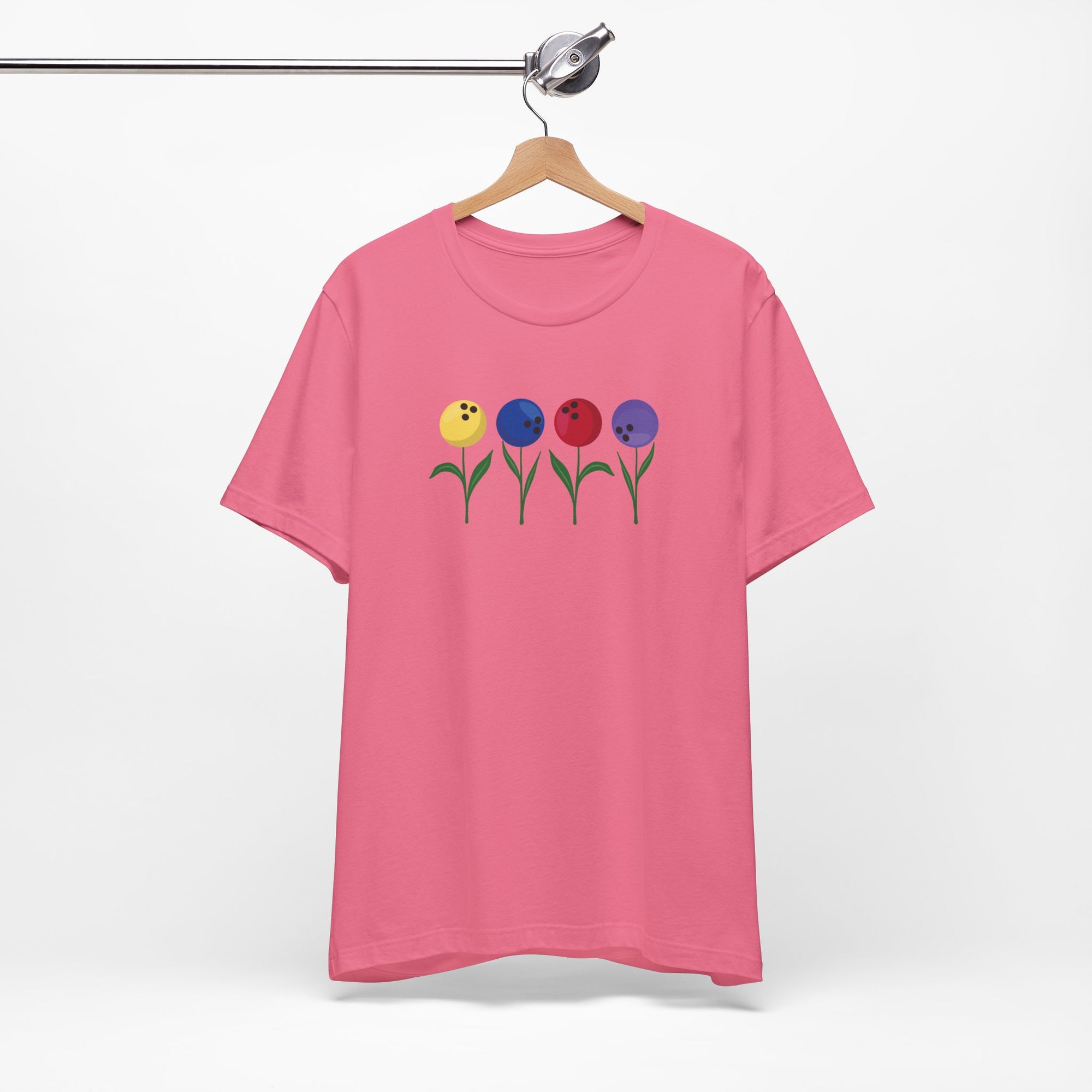 Pink t-shirt with colorful flowers made out of bowling balls, on a hanger against a white background