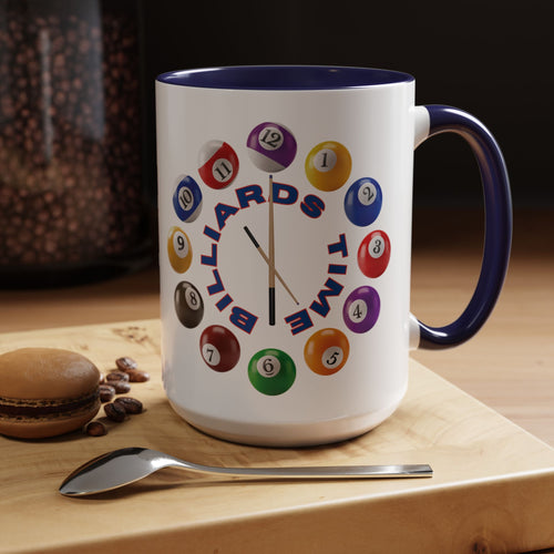 A white ceramic coffee mug with dark blue accents on the handle and interior, with the text "Billiards Time" surrounded by a clock made up of colorful billiard balls and cue sticks, in a coffee shop setting