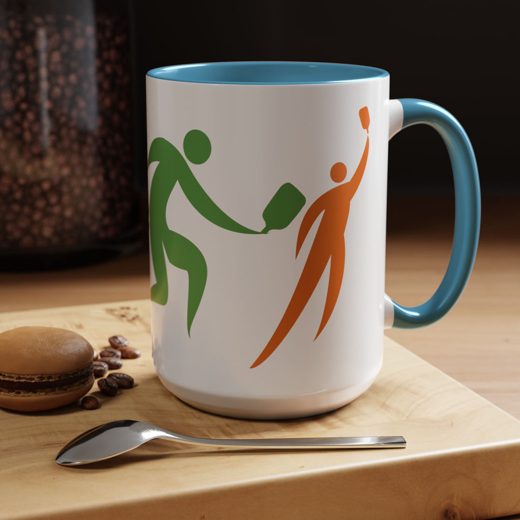 Ceramic coffee mug with blue accents on the handle and interior, featuring an image of four colorful pickleball player drawings playing pickleball in a coffee shop setting.