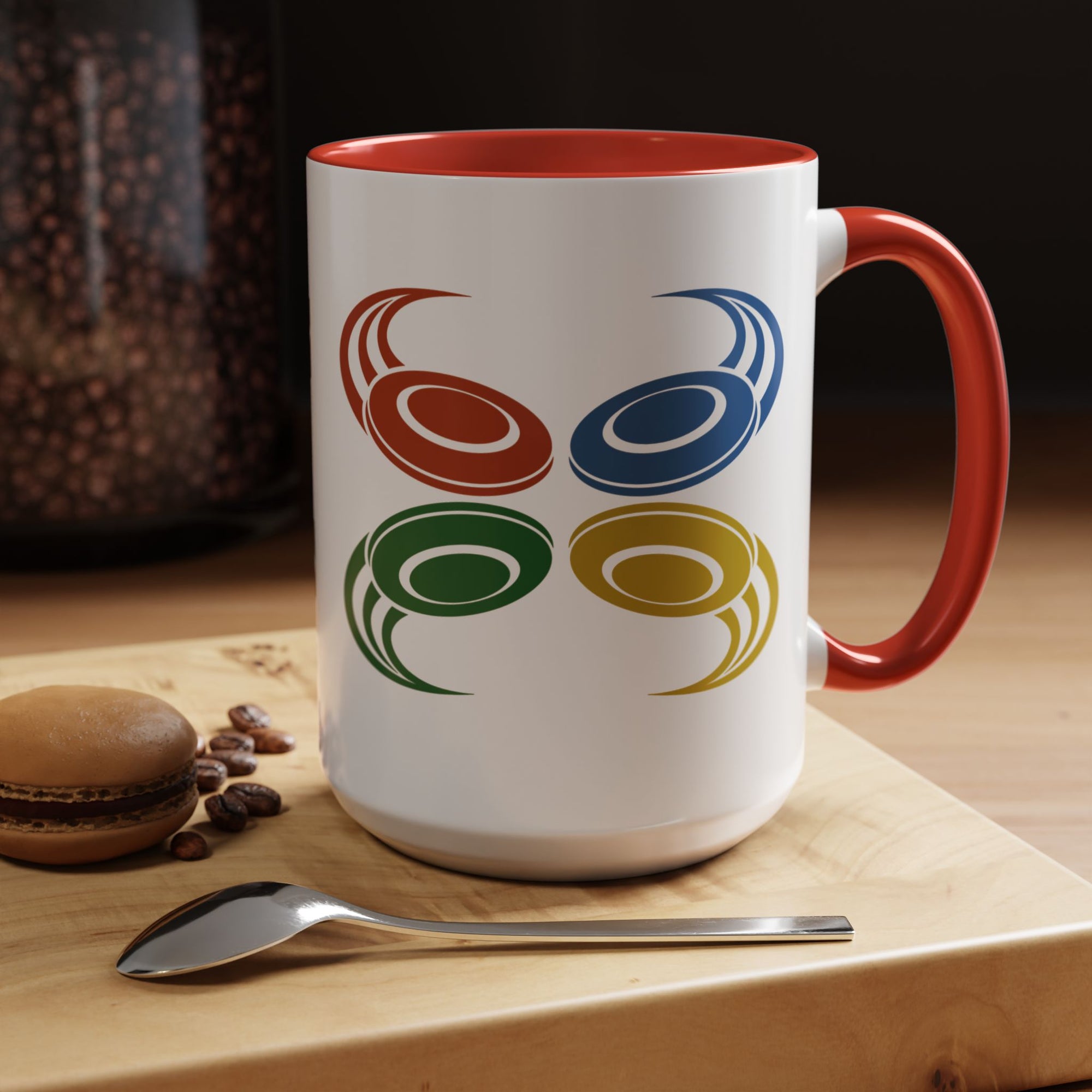 A ceramic mug with red accents on the handle and interior, featuring a graphic of four colorful disc golf discs in a coffee shop setting