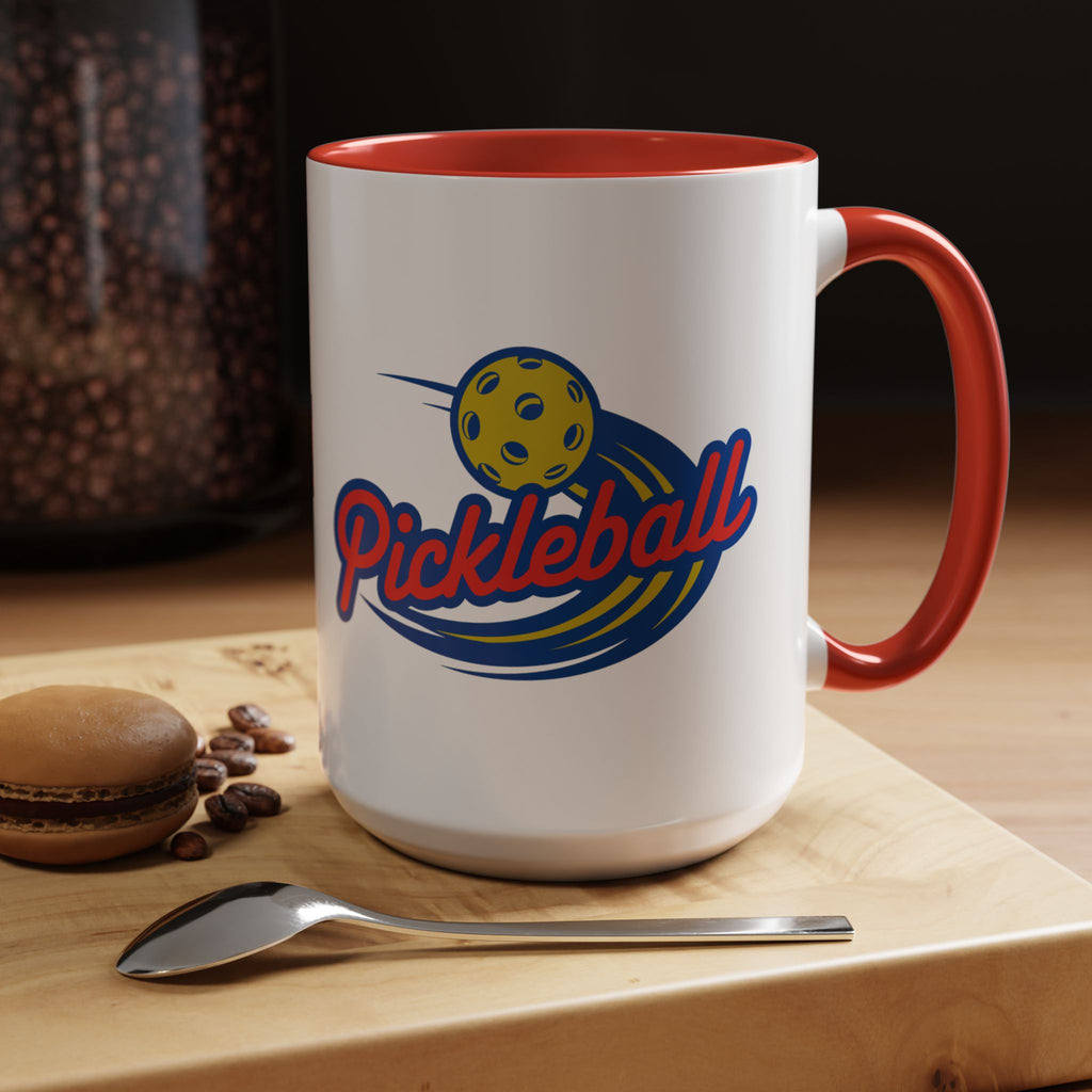 Ceramic coffee mug with red accents on the handle and interior, with a classic pickleball logo featuring the word pickleball and a yellow pickleball with motion lines, in a coffee shop setting.