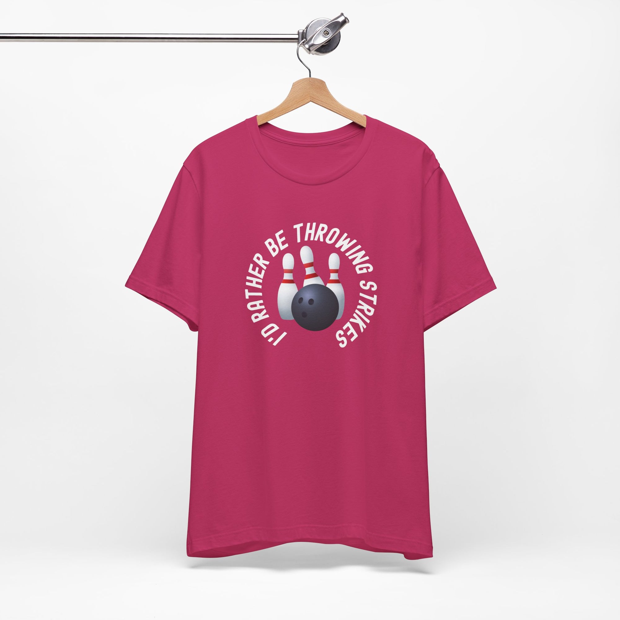 Pink t-shirt with bowling pins and a bowling ball and text saying "I'd Rather Be Throwing Strikes" on a hanger against a white background