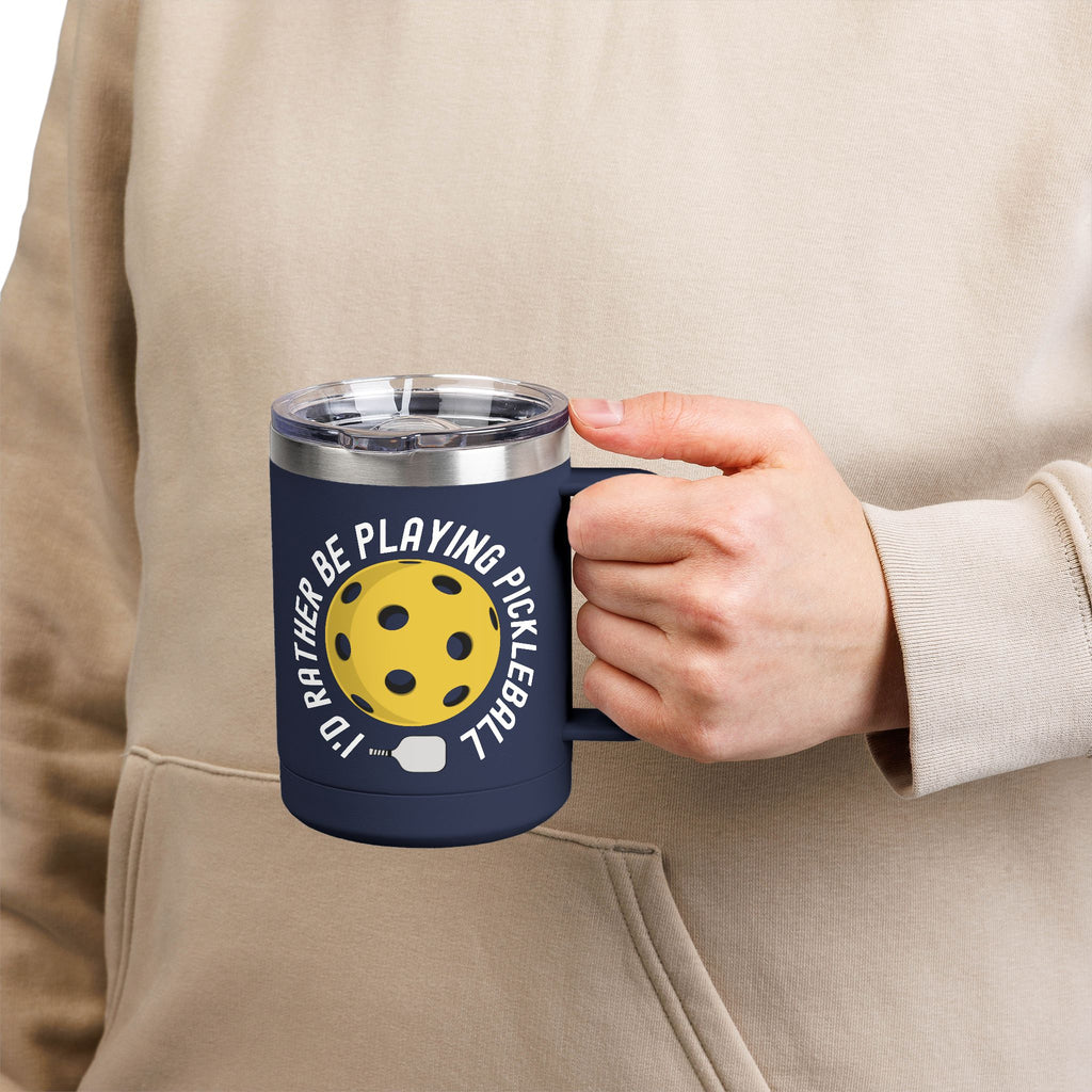 Man holding a navy blue travel mug with lid with a yellow pickleball graphic and the text "I'd Rather Be Playing Pickleball" on a white background