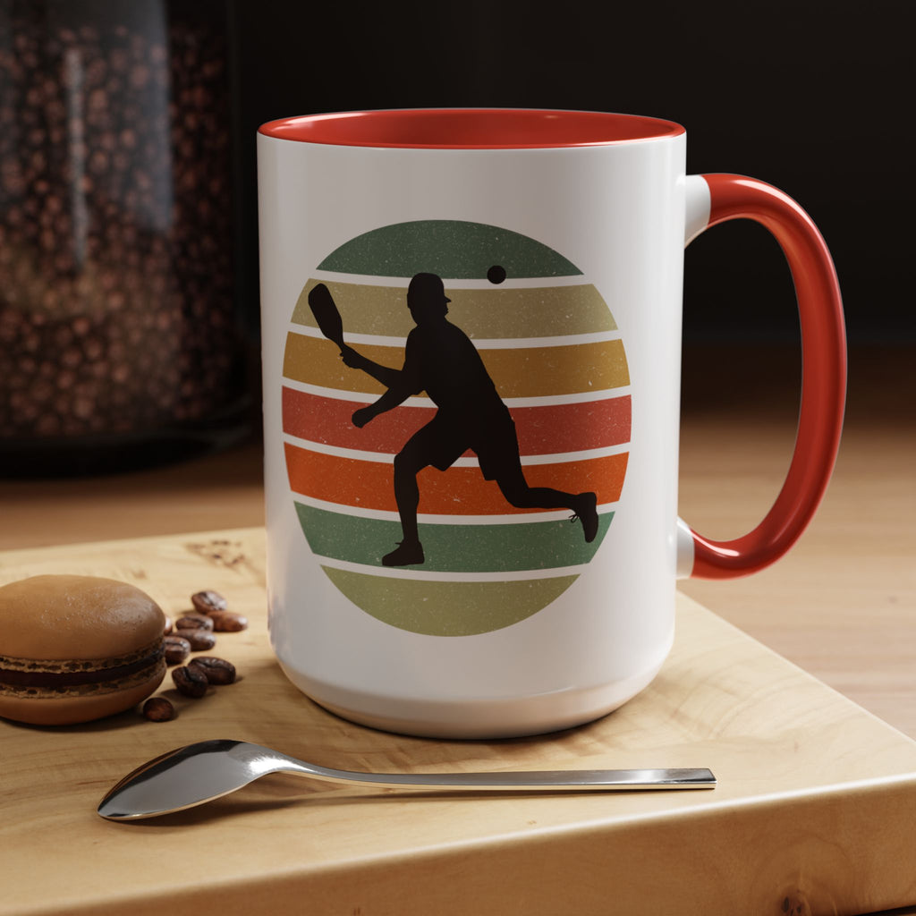 Mug with red accent with a silhouette of a person playing pickleball against a colorful circular background on a white background.