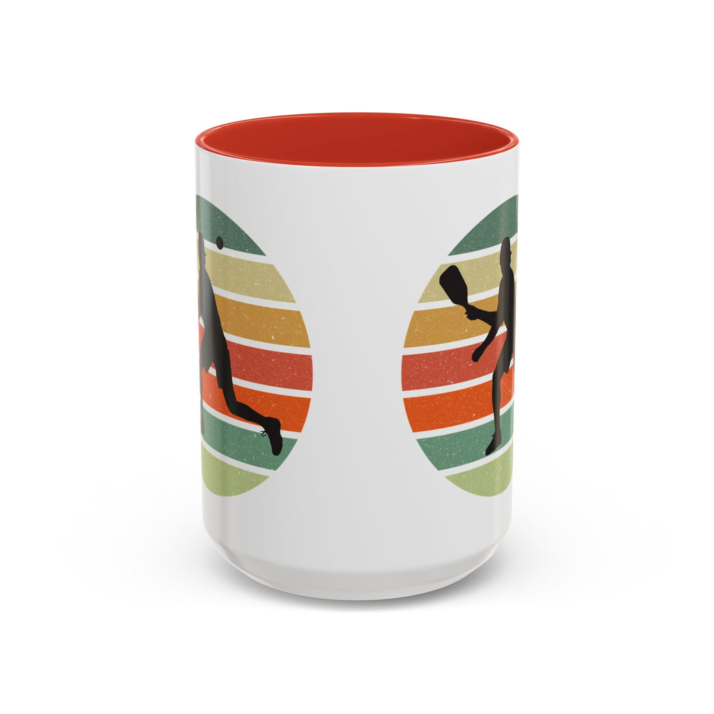 Coffee mug with red accent with a silhouette of a person playing pickleball against a colorful circular background on a white background.