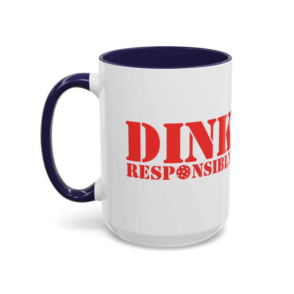 A ceramic coffee mug with dark blue accents on the handle and interior, with red text 'DINK RESPONSIBLY' with a pickleball replacing the "O" in "Responsibly" against a white background