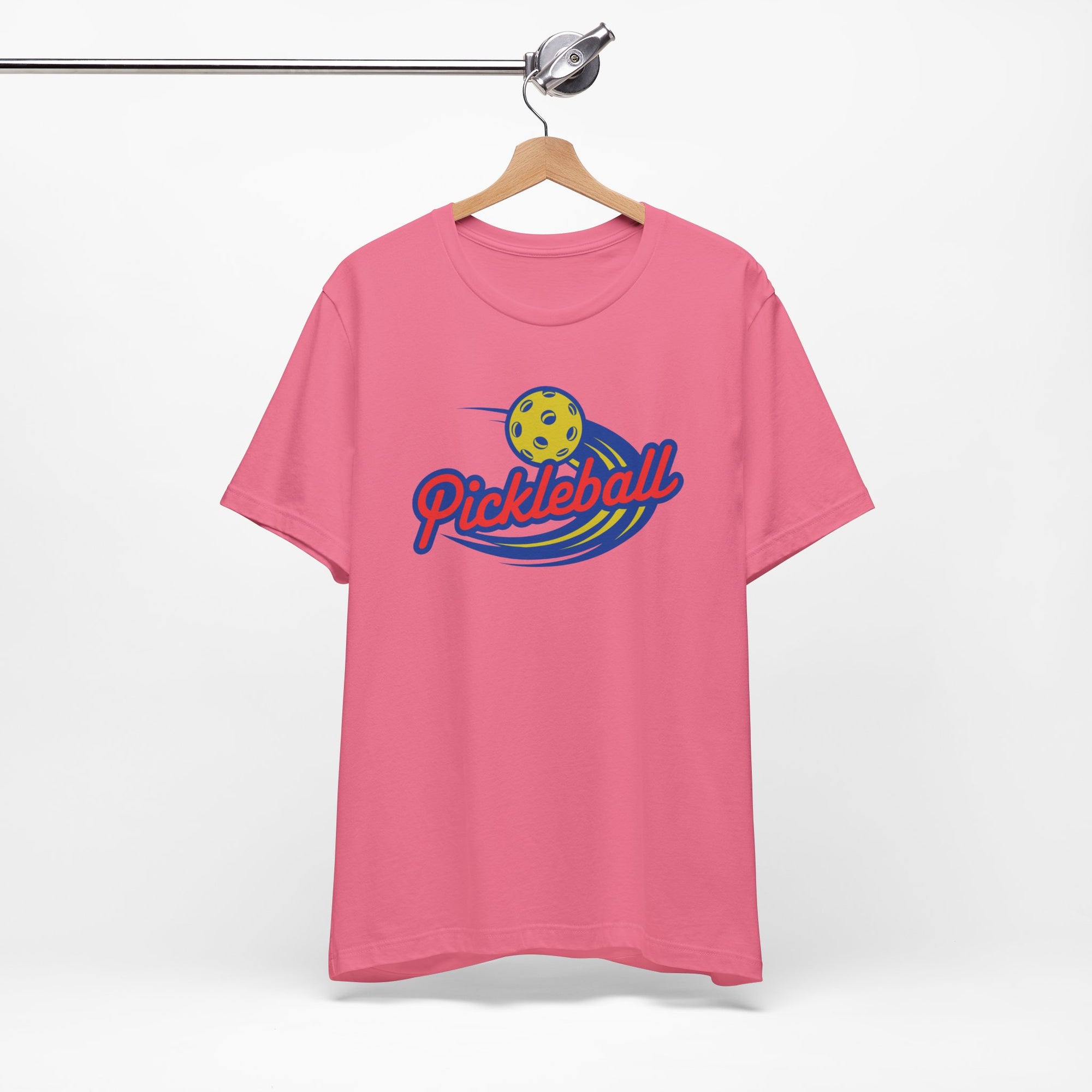 Pink t-shirt with a classic pickleball logo featuring the word pickleball and a yellow pickleball with motion lines, on a hanger against a white background