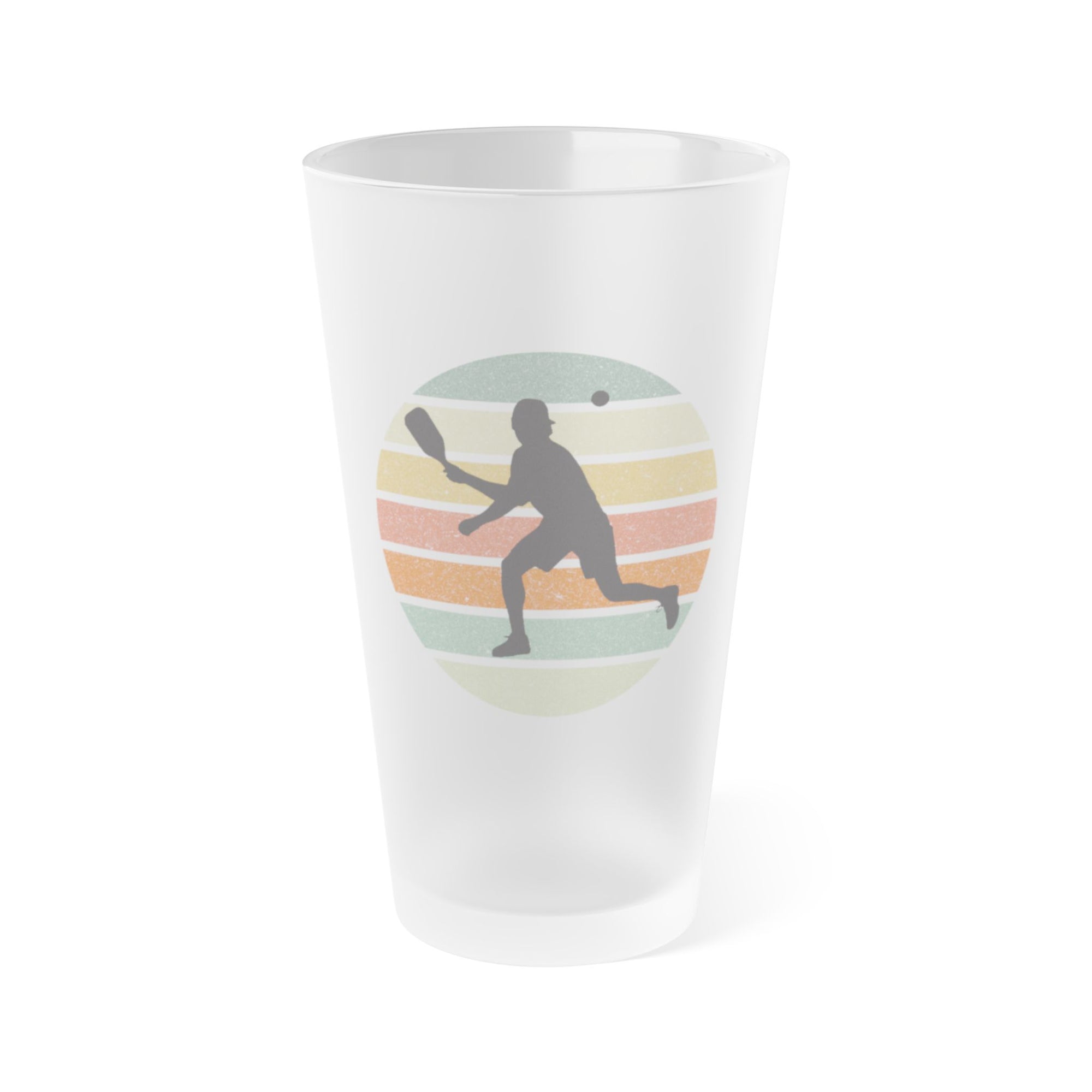 A frosted pint glass with a silhouette of a pickleball player over a circle of colorful lines, on a white background
