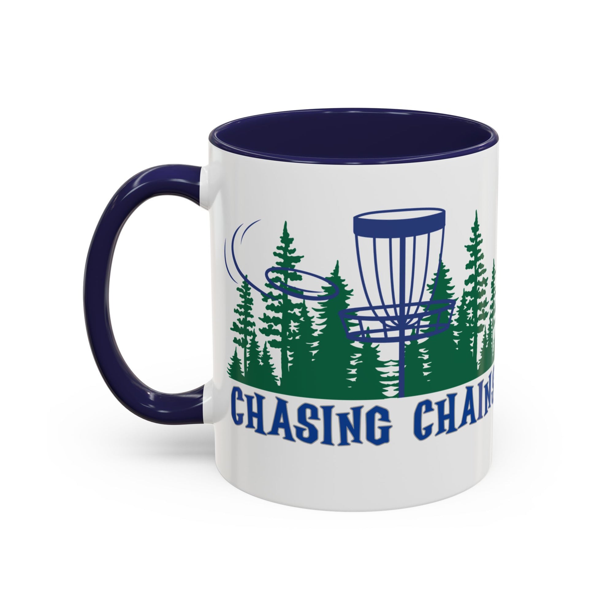 A ceramic coffee mug with dark blue accents on the handle and interior, with 'Chasing Chains' graphic featuring a flying disc golf disc and basket and chains in front of a scenic evergreen tree landscape, against a white background