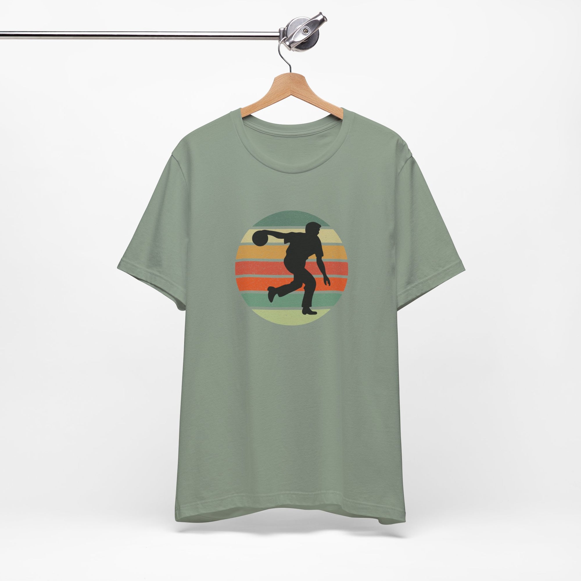 Teal t-shirt with a graphic of a silhouette of a bowler over a colorful retro image, hanging on a wooden hanger against a white background.