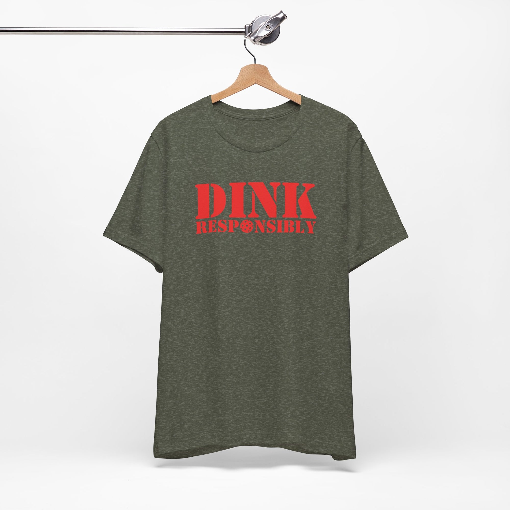 Military green t-shirt with red text 'DINK RESPONSIBLY' with a pickleball replacing the "O" in "Responsibly" on a hanger against a white background