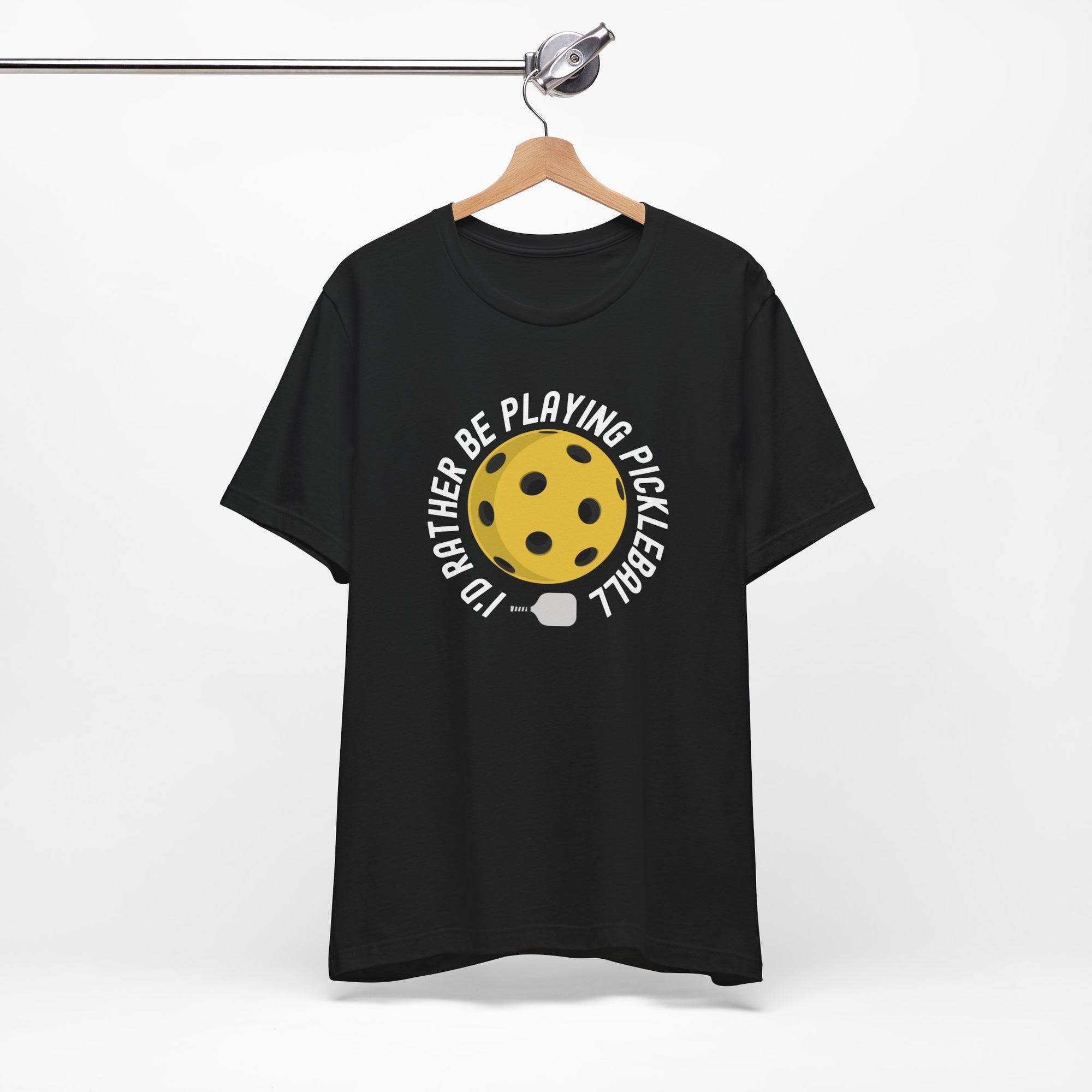 Black t-shirt with a yellow pickleball and white pickleball paddle and the text "I'd Rather Be Playing Pickleball" on a hanger against a white background