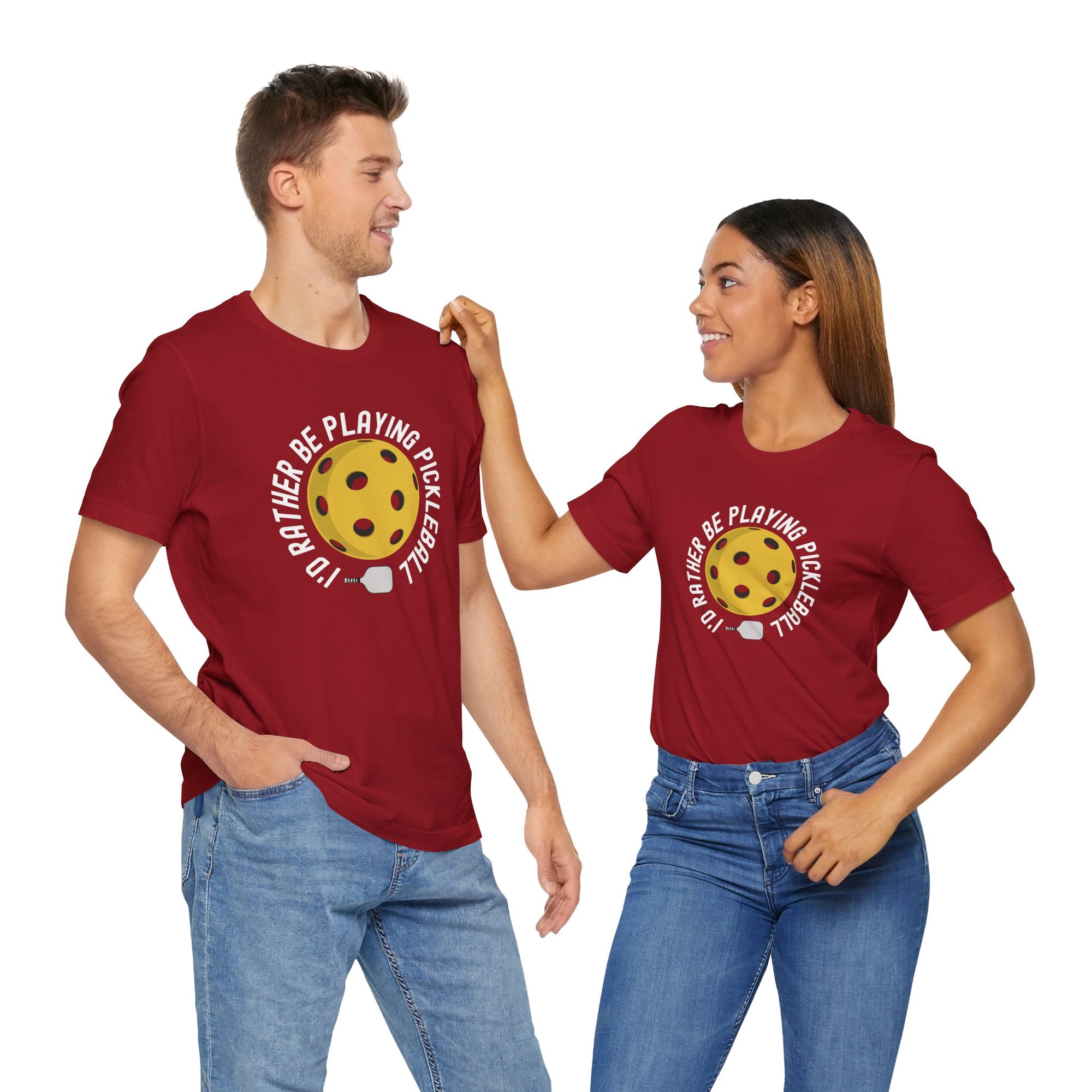 A man and a woman wearing a red t-shirt with a yellow pickleball and white pickleball paddle and the text "I'd Rather Be Playing Pickleball" on a hanger against a white background