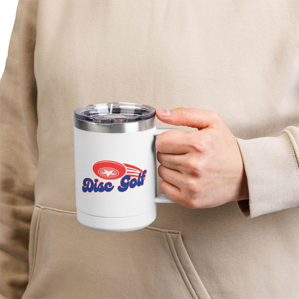 A person holding a white travel coffee mug tumbler with handle and lid with 'Disc Golf' in a blue script text outlined in red and disc golf with motion trails