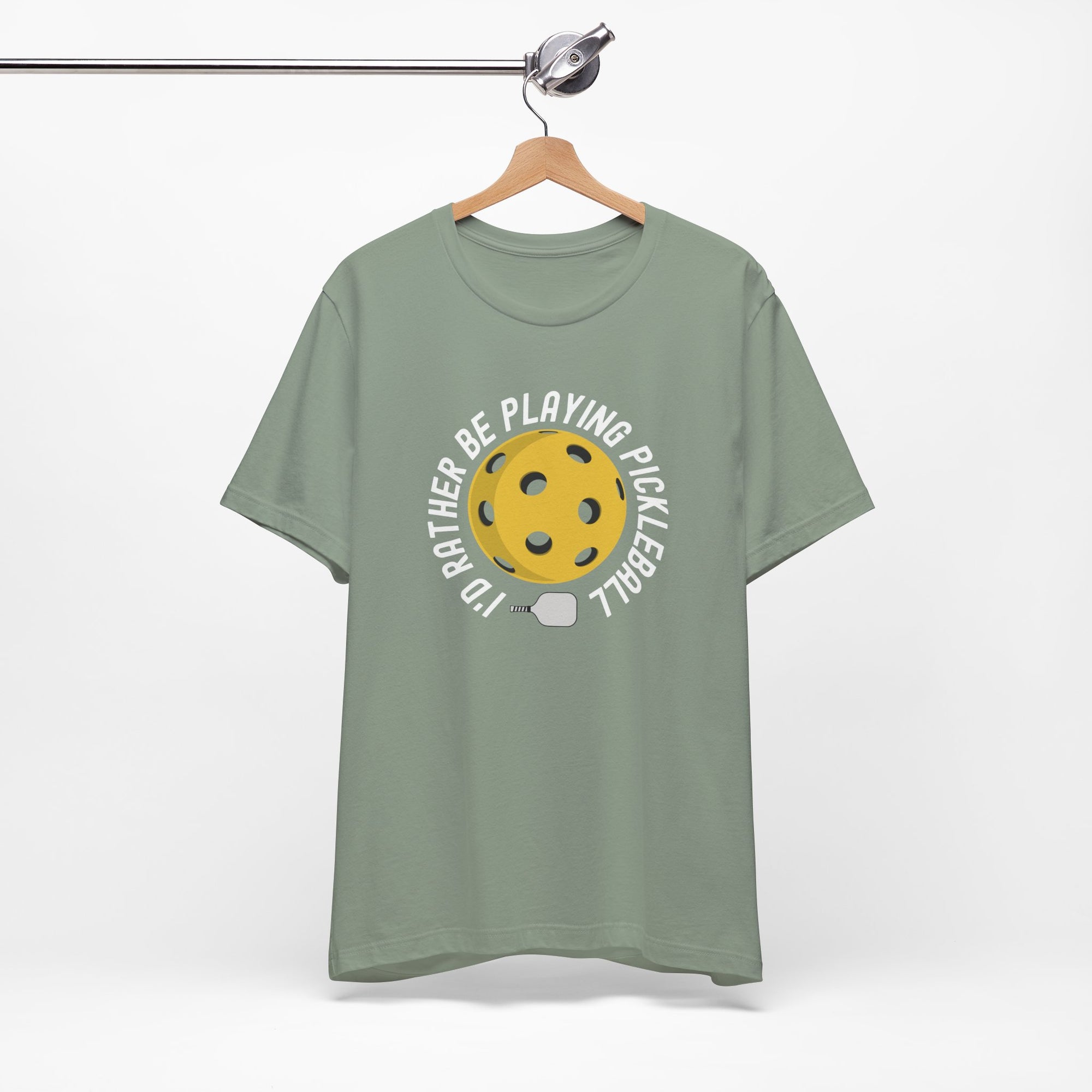 Teal t-shirt with a yellow pickleball and white pickleball paddle and the text "I'd Rather Be Playing Pickleball" on a hanger against a white background