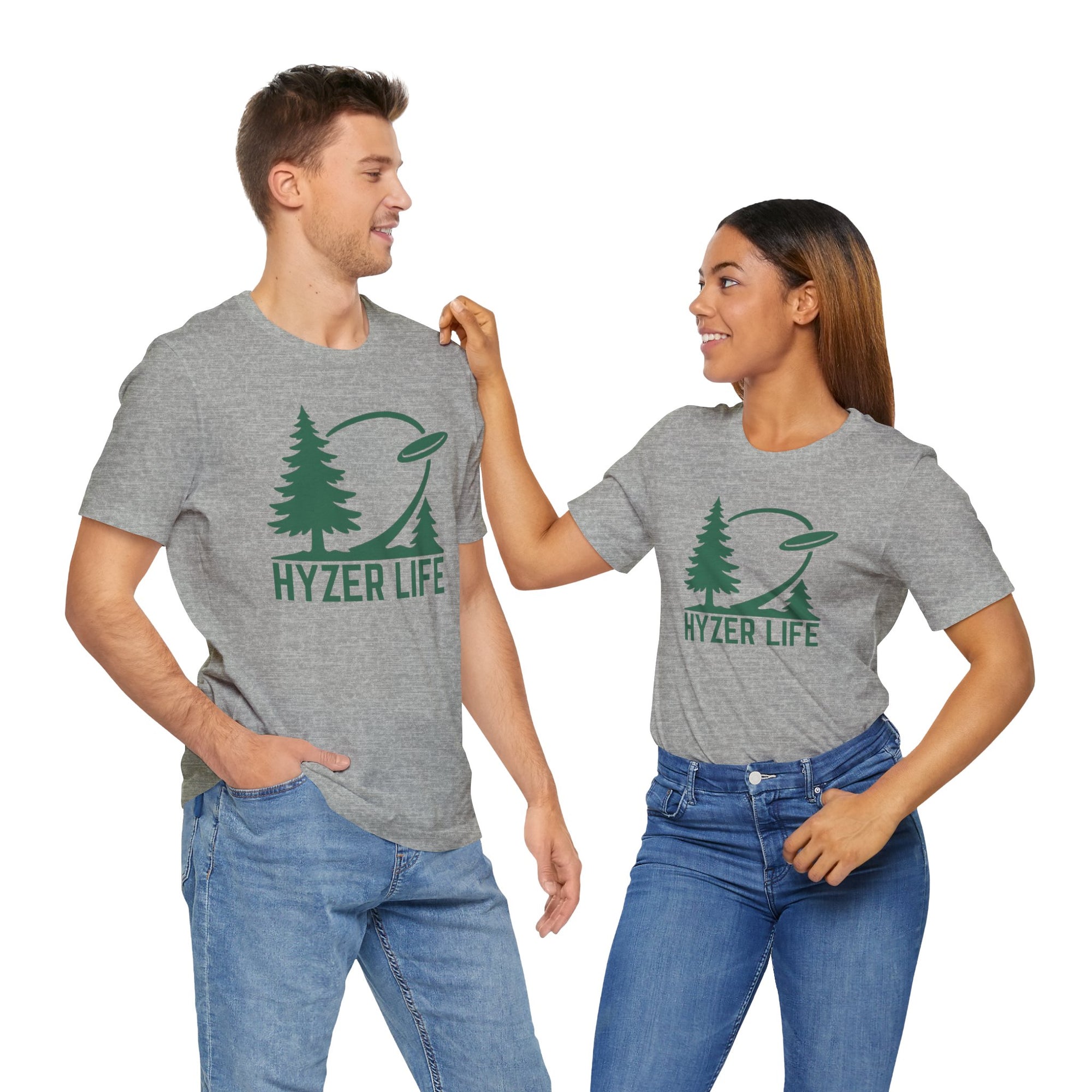 A man and a woman both wearing a gray t-shirt with green graphic of trees and a disc golf flying with the words 'HYZER LIFE' below the image,against a white backgroud