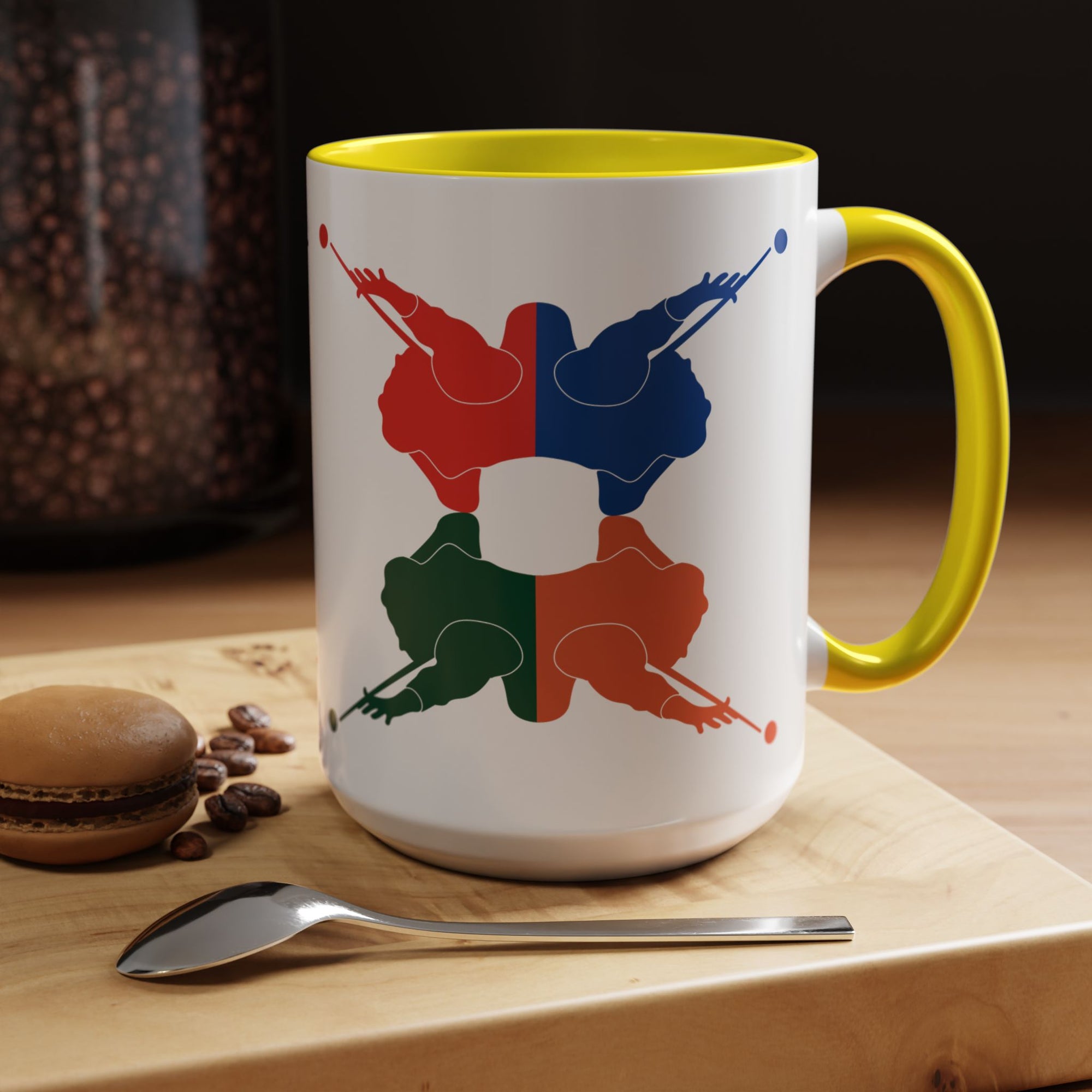 A white ceramic coffee mug with yellow accents on the handle and interior, with colorful graphic of 4 billiards player silhouettes in a pop art style, in a coffee shop setting