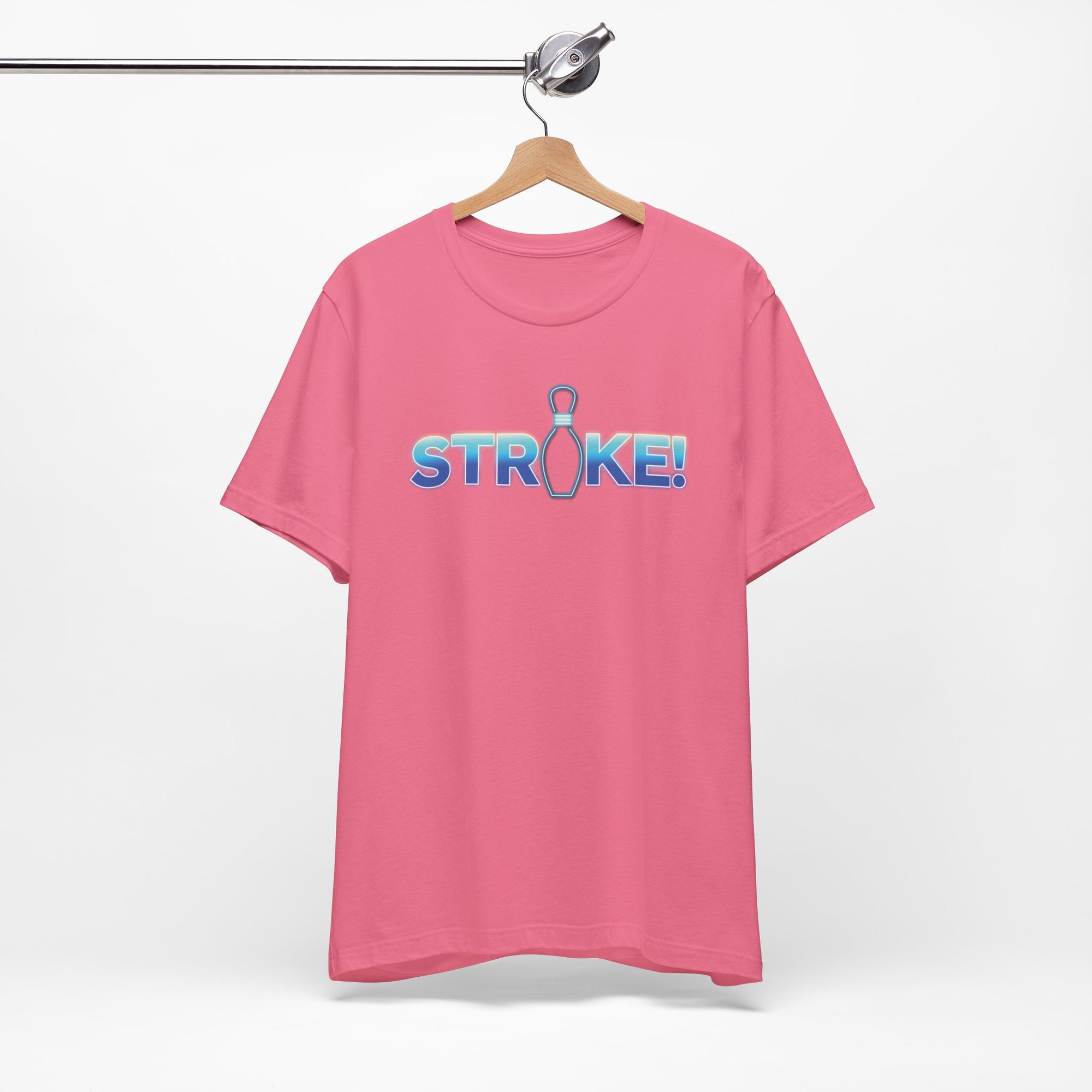 Pink bowling t-shirt with 'STRIKE!' with the "I" replaced by a bowling pin, on a hanger against a white background
