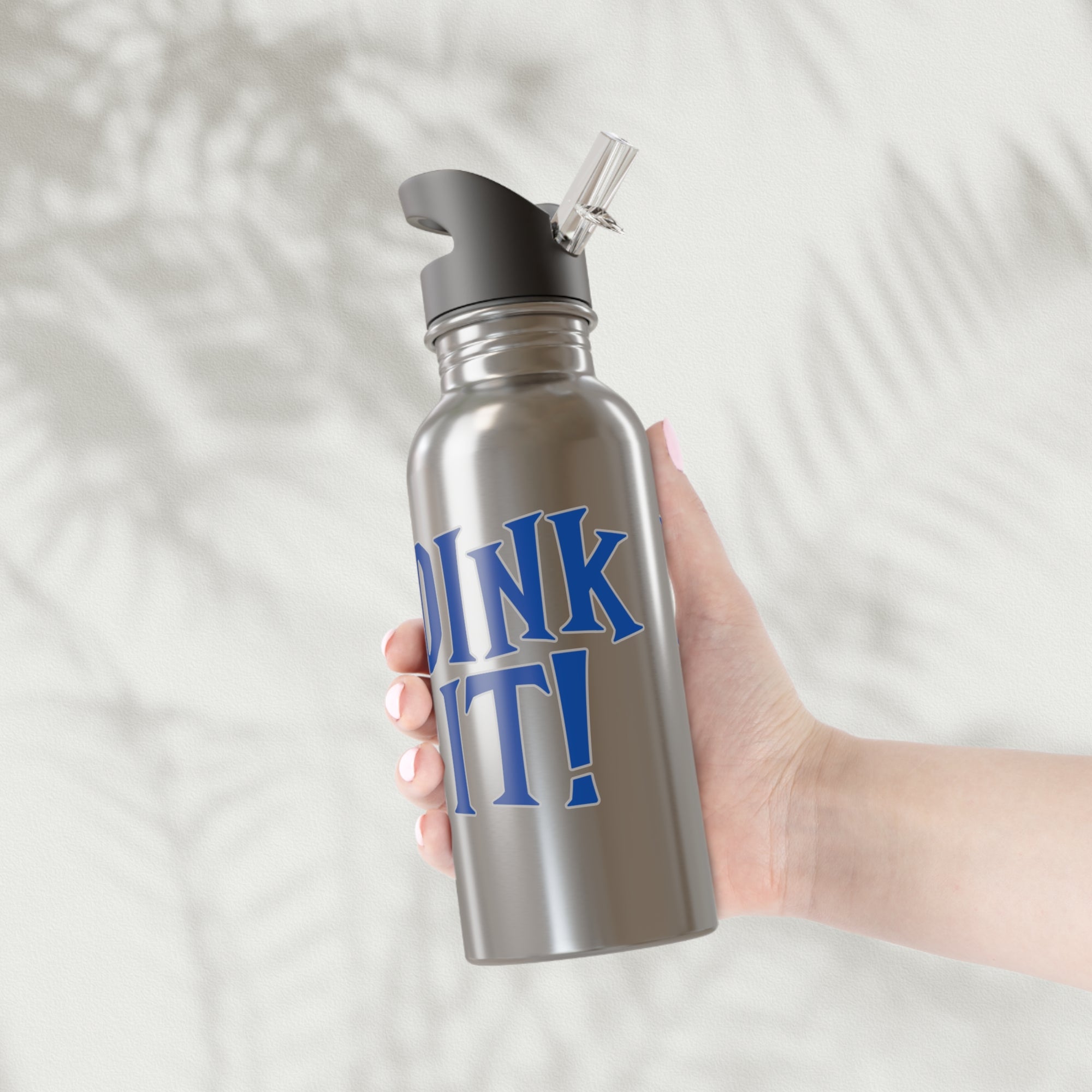 A person holding a stainless steel water bottle with lid featuring the words 'DINK IT!' text in blue and outlined in gray, against a white background