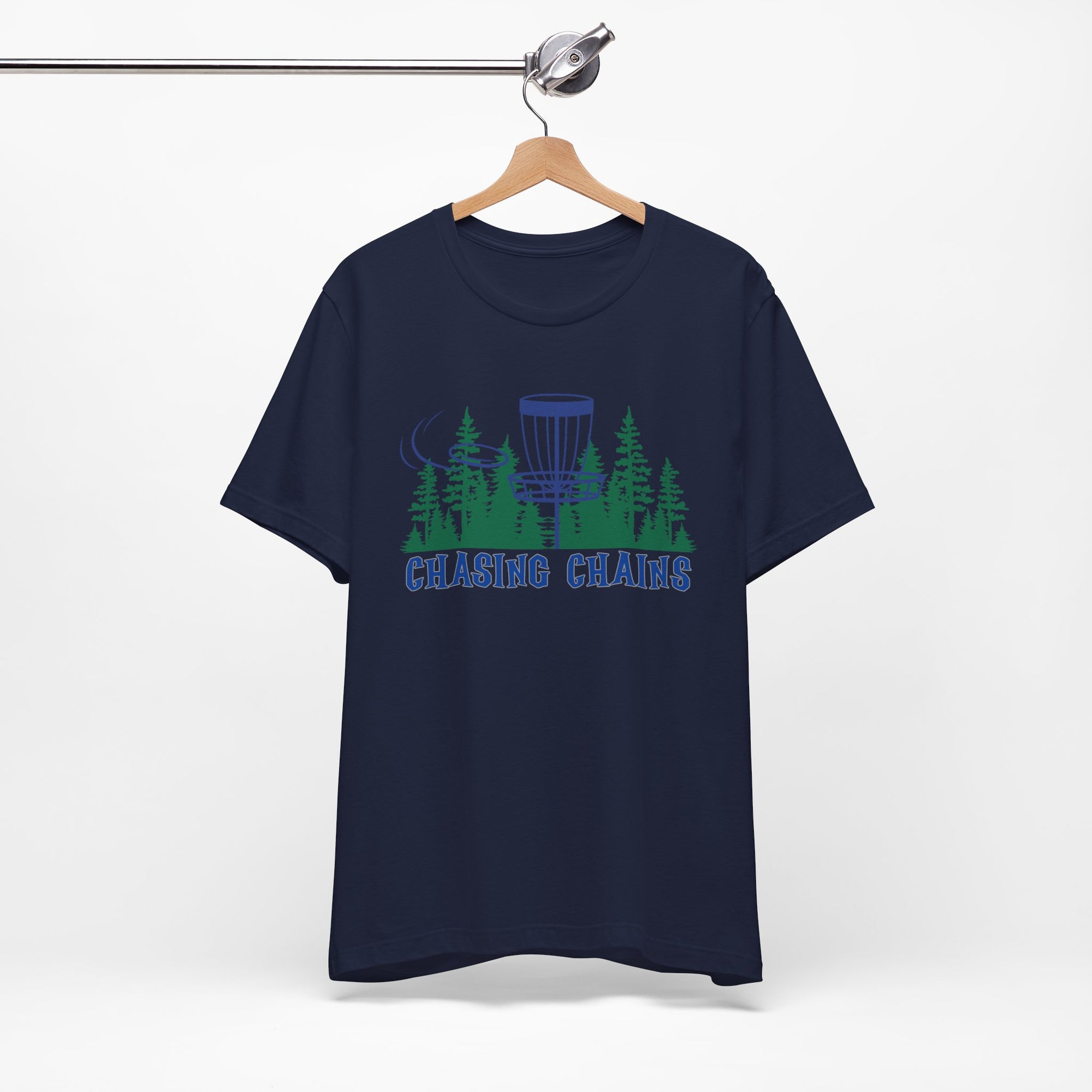 Navy blue t-shirt with 'Chasing Chains' graphic featuring a flying disc golf disc and basket and chains in front of a scenic evergreen tree landscape, on a hanger against a white background