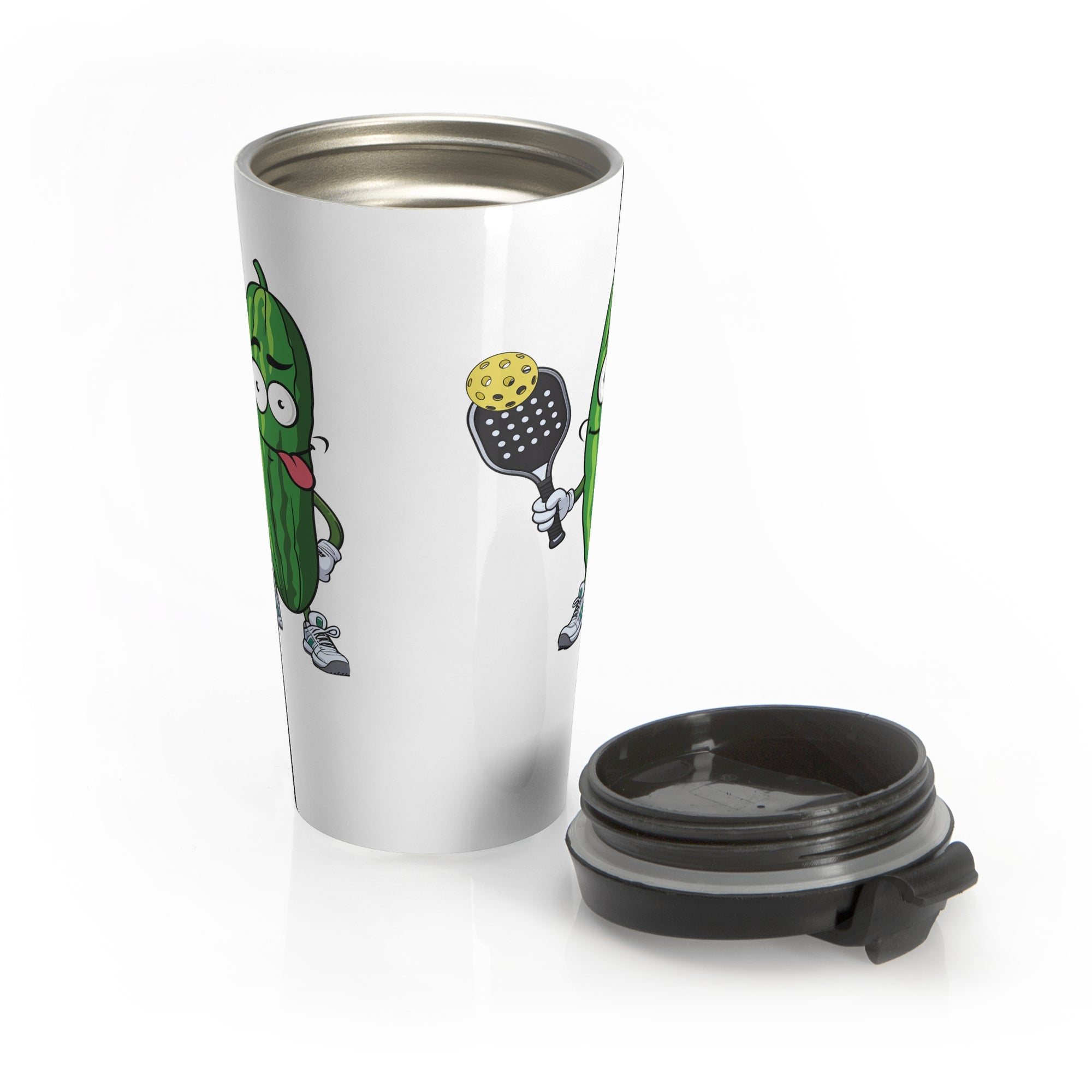 A white travel coffee mug with a lid next to the mug, featuring a cartoon pickle with googly eyes and his tongue sticking out, holding a pickleball paddle with a yellow pickleball, against a white background