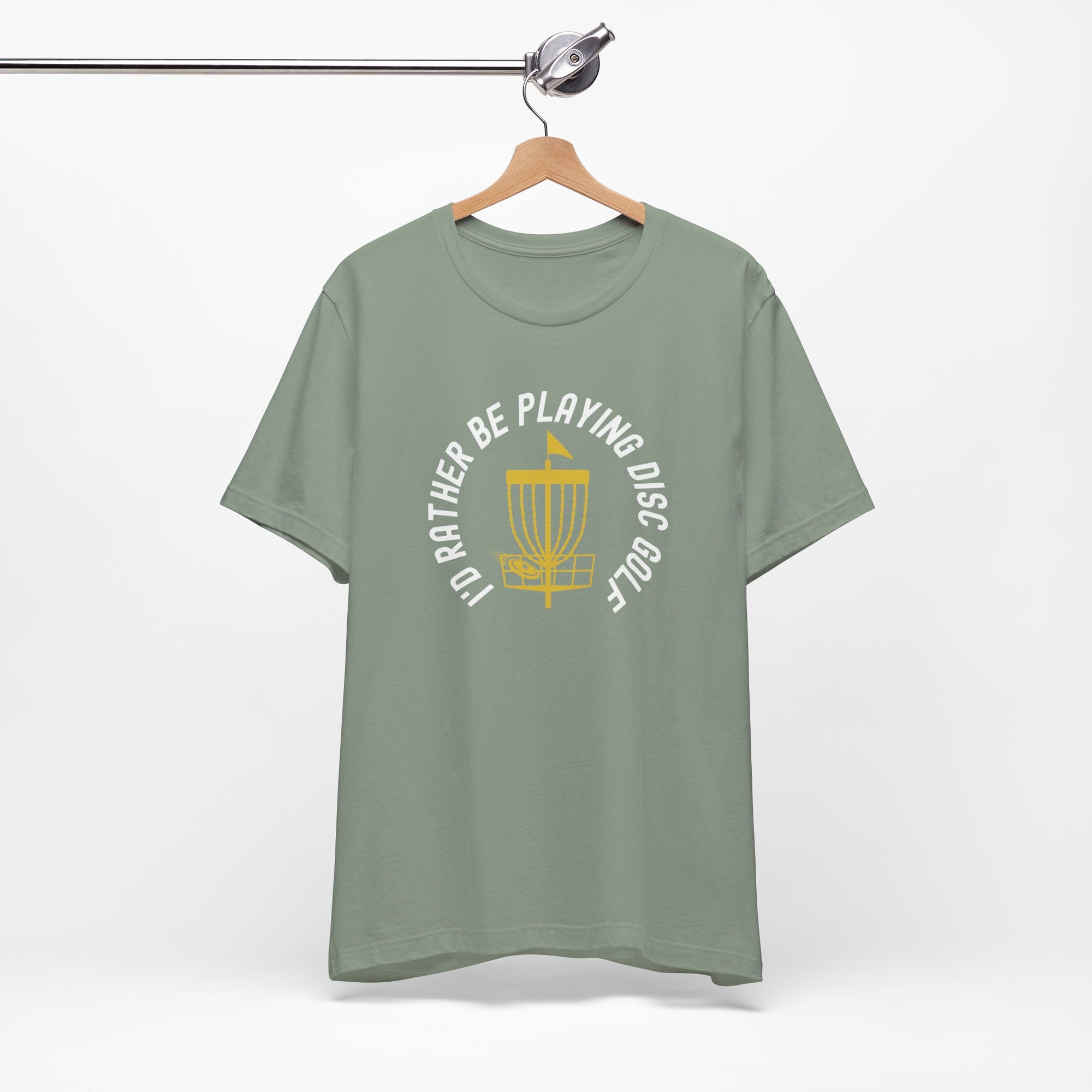 Light green t-shirt with a graphic of disc golf chains, basket, and disc and text that says "I'd Rather Be Playing Disc Golf" on a hanger against a white background