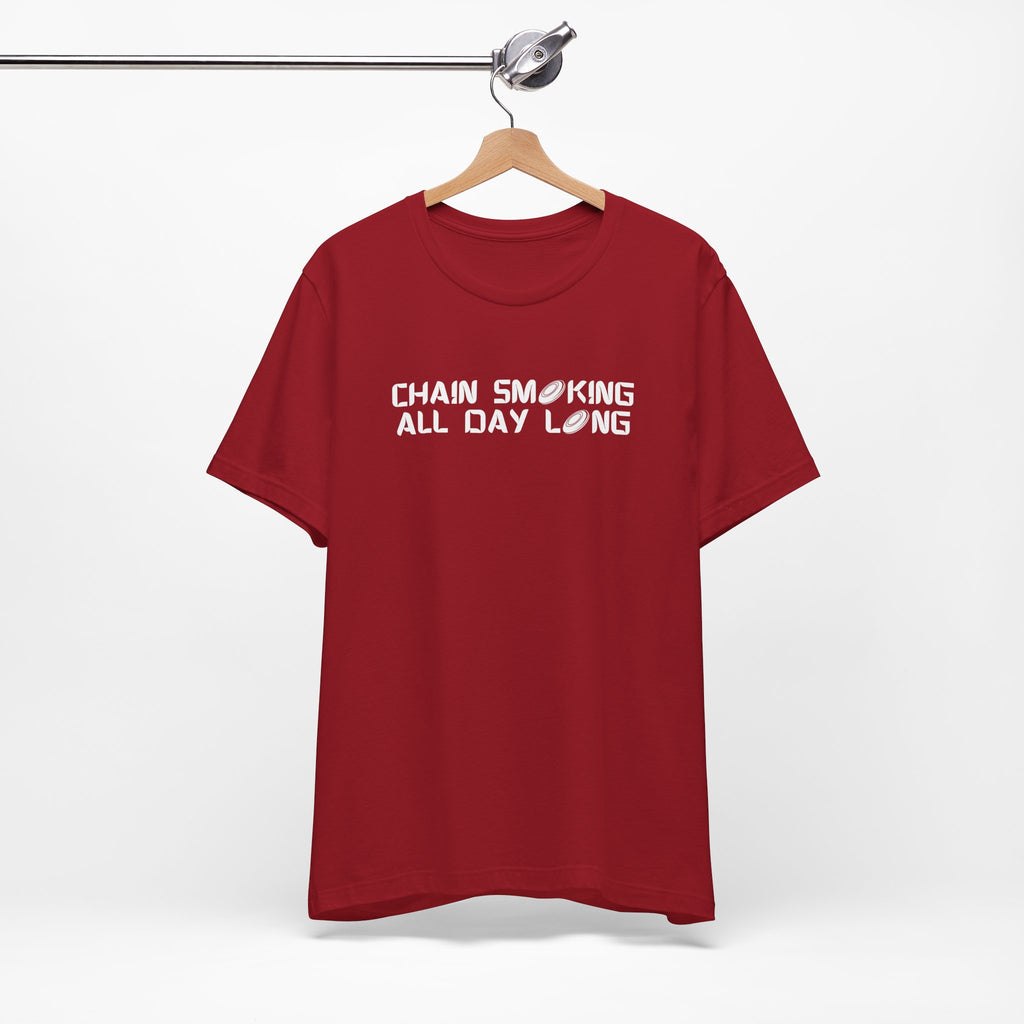 Red t-shirt with 'CHAIN SMOKING ALL DAY LONG' text with the O's replaced by disc golf discs, on a hanger against a white background