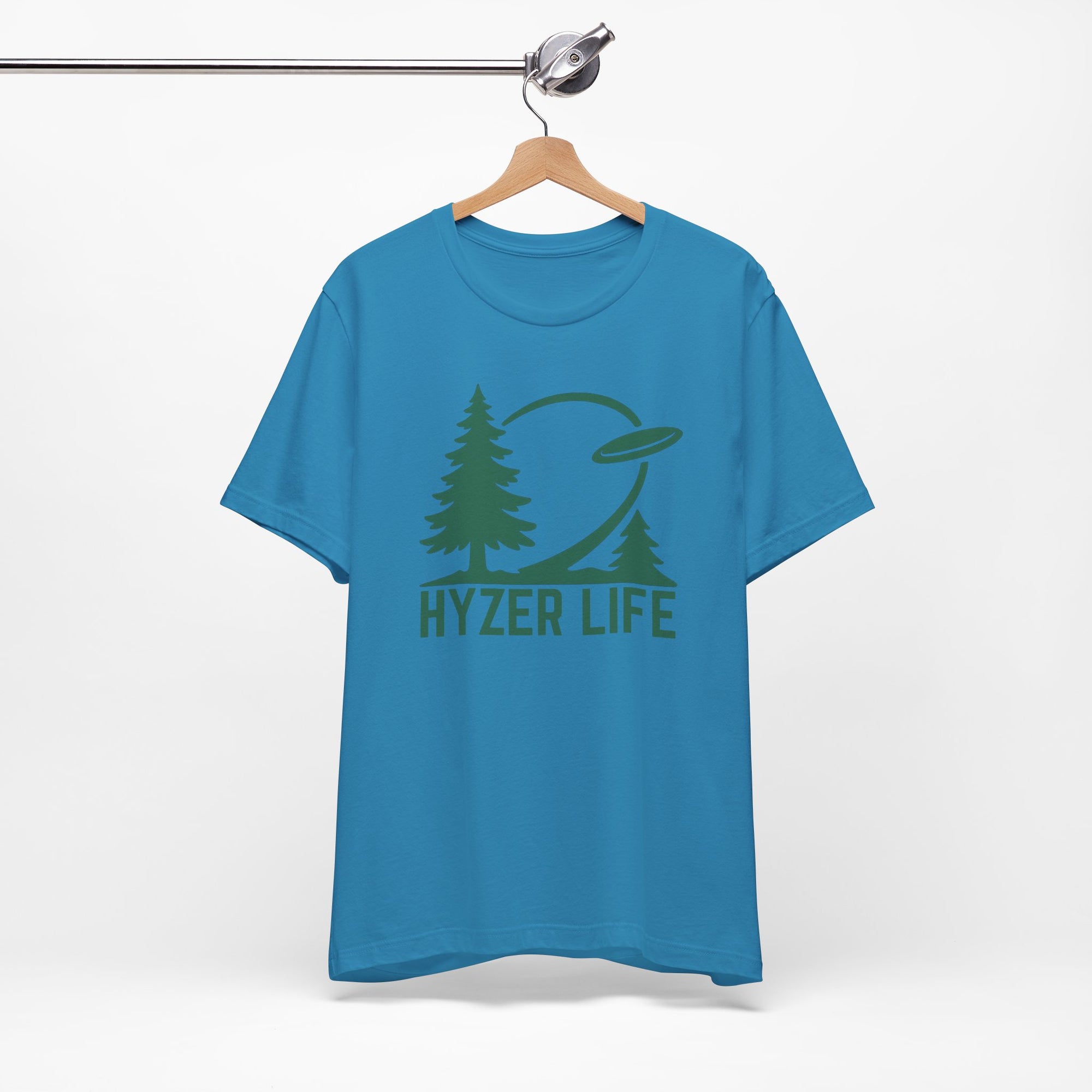 Blue t-shirt with green graphic of trees and a disc golf flying with the words 'HYZER LIFE' below the image, on a hanger against a white backgroud